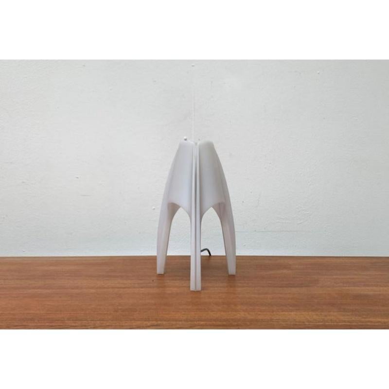 Rara lámpara de mesa trípode del fabricante italiano Martini.

La lámpara está hecha totalmente de plástico. Esto también permite conseguir una forma llamativa. Las tres patas tienen un elemento usado, transparente, que puede atravesar toda la