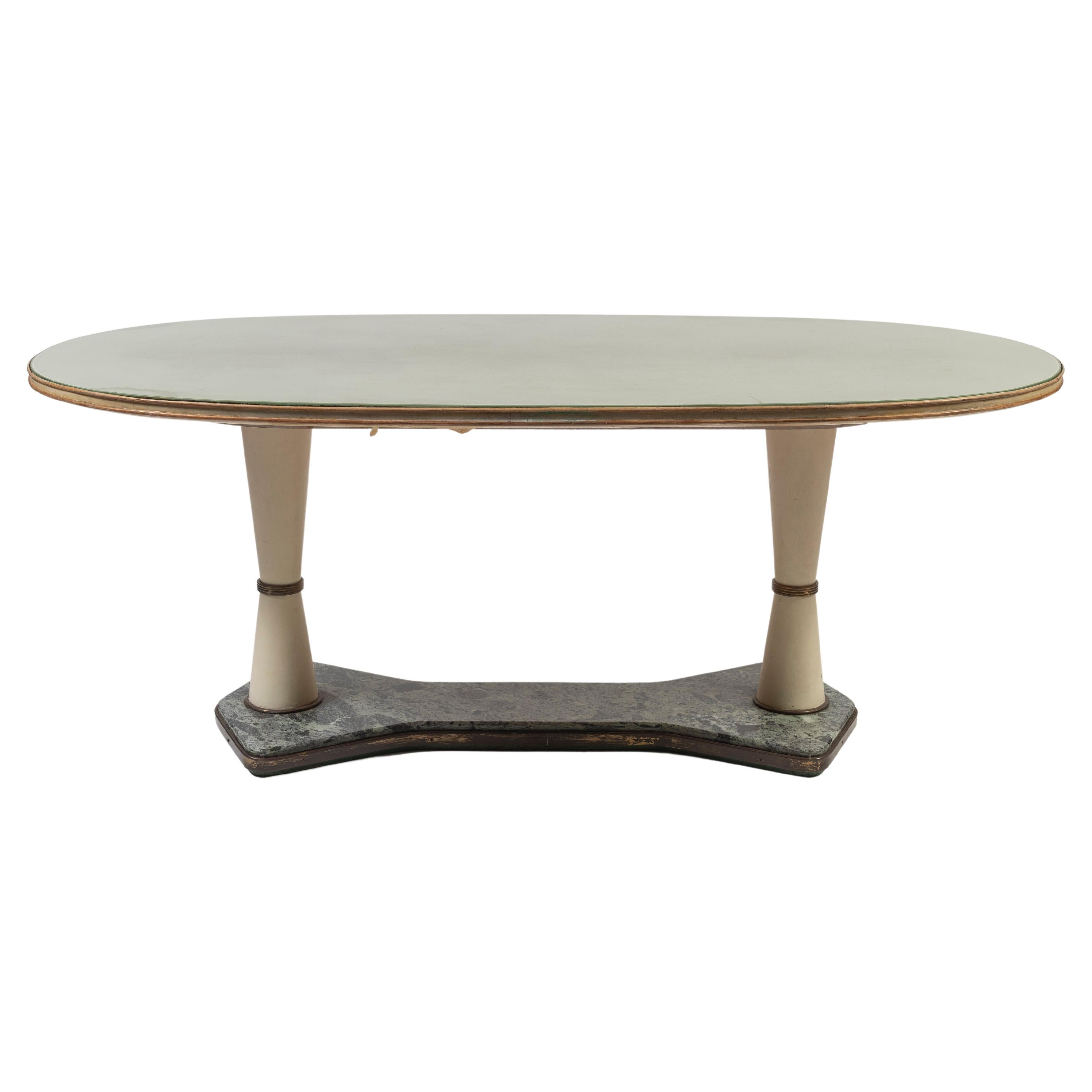 1940's Art Deco dining or center table, in the style of Vittorio Dassi, is made in two pieces, and composed of a green marble and metal base, painted wooden legs and an oval reverse-painted top in glass, banded in wood. The elegant and symmetrical