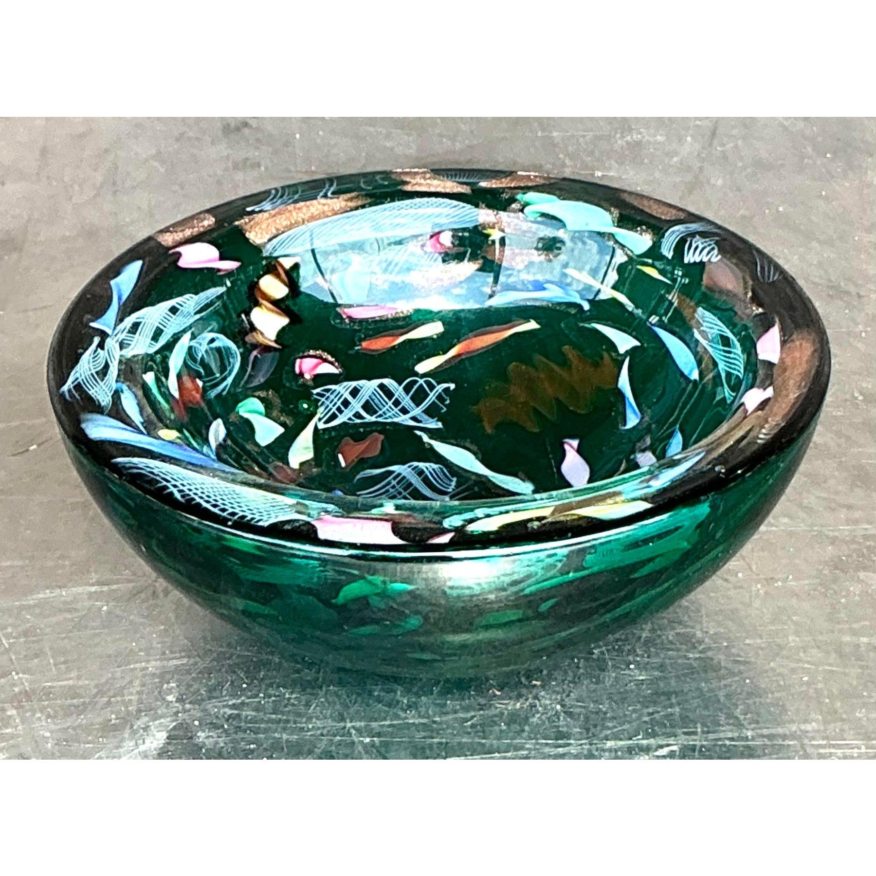 This stunning vintage Italian art glass bowl showcases exquisite Murano-style craftsmanship, featuring a mesmerizing swirl of vibrant green, blue, and gold flecks. The hand-blown glass design creates an intricate interplay of colors and patterns,