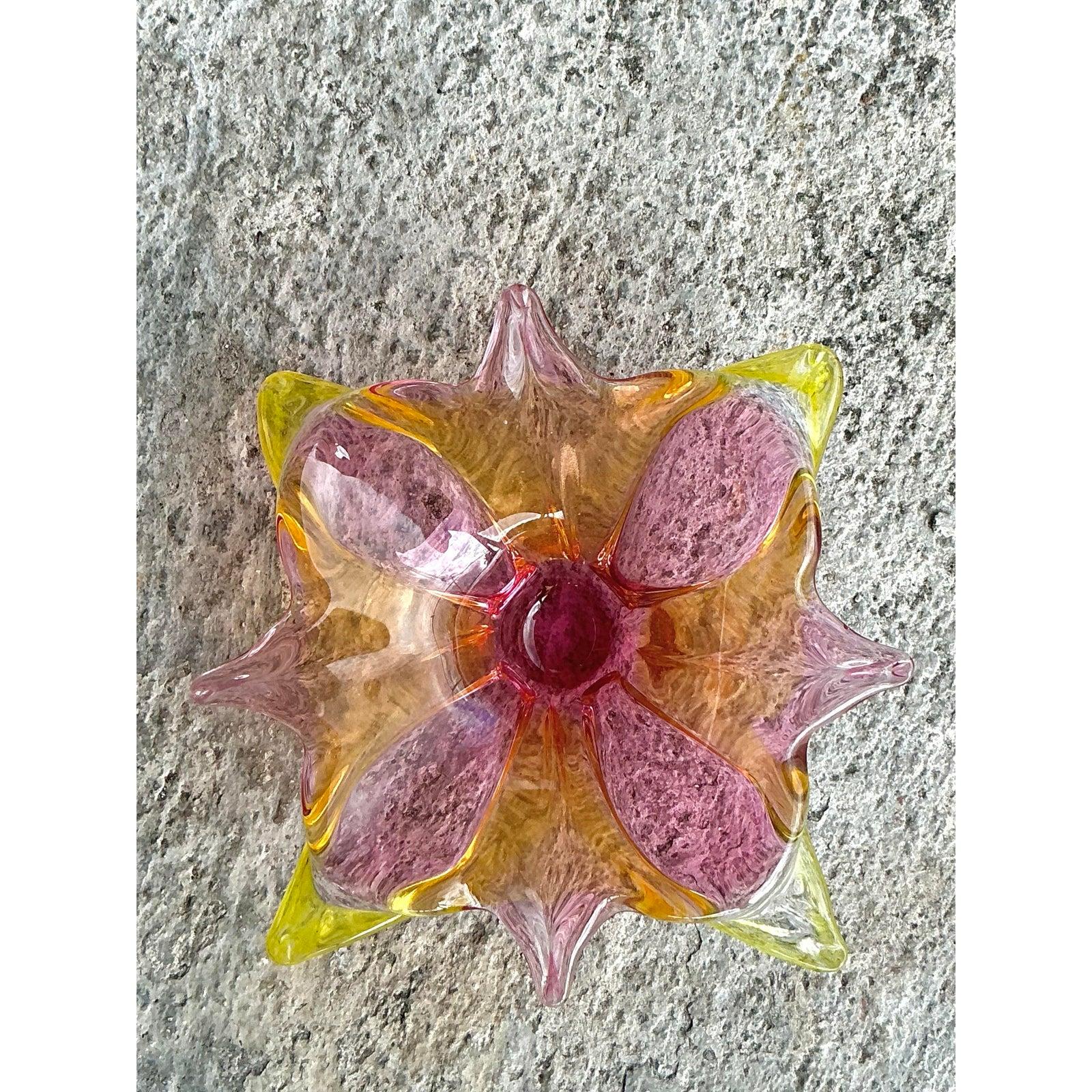 This vintage Italian art glass bowl, inspired by the renowned Murano glassmaking tradition, is a stunning example of craftsmanship and elegance. Featuring a radiant combination of pink, amber, and yellow hues, this hand-blown piece exhibits a fluid
