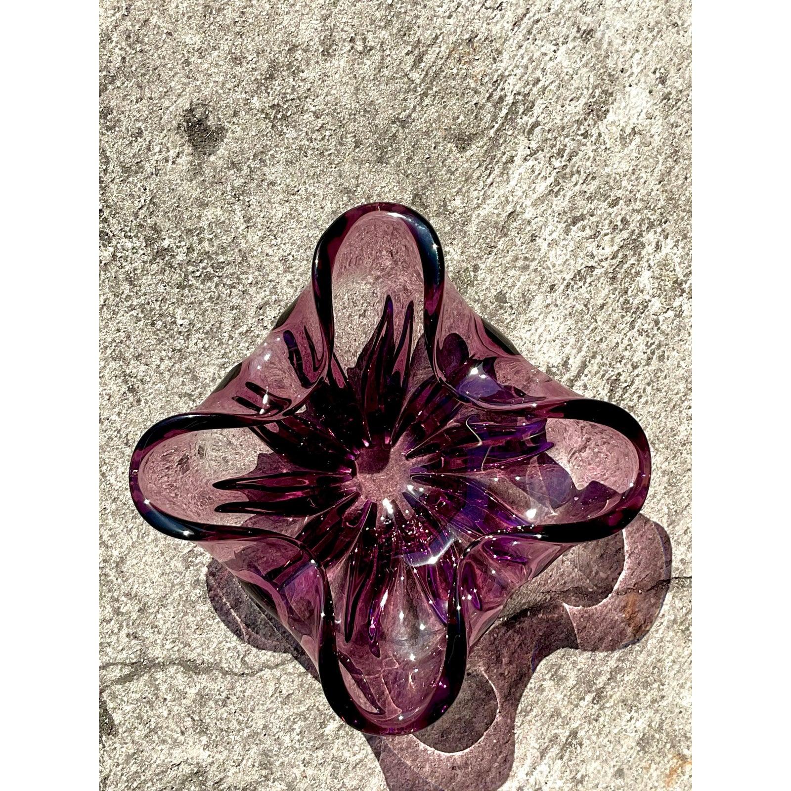 Infuse your space with sculptural charm and Italian artistry through this vintage art glass bowl, inspired by the legendary Murano glassmakers. Hand-blown with graceful curves and a captivating square form, this piece showcases rich amethyst tones