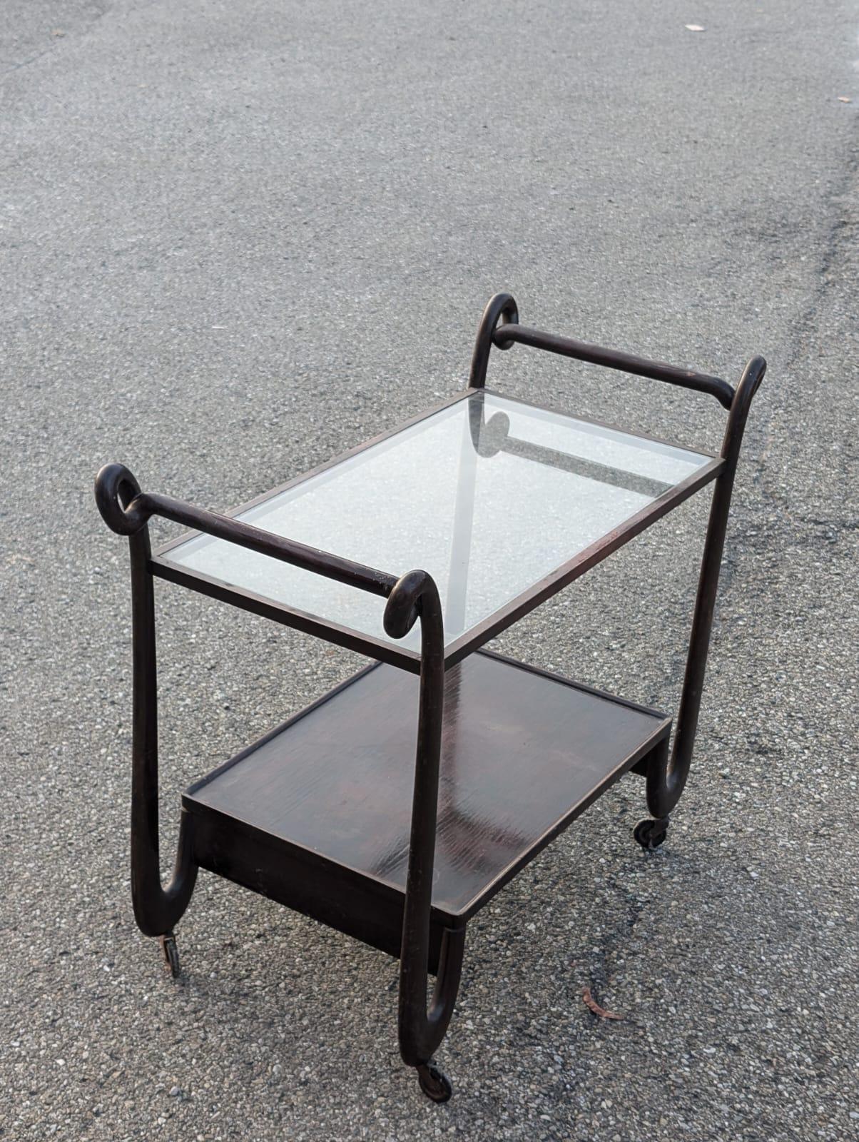 Experimente la sofisticación de la época de mediados de siglo con este carro de bar italiano vintage. Fabricada en madera de alta calidad, esta pieza muestra la estética atemporal del diseño moderno de mediados de siglo, caracterizado por sus líneas