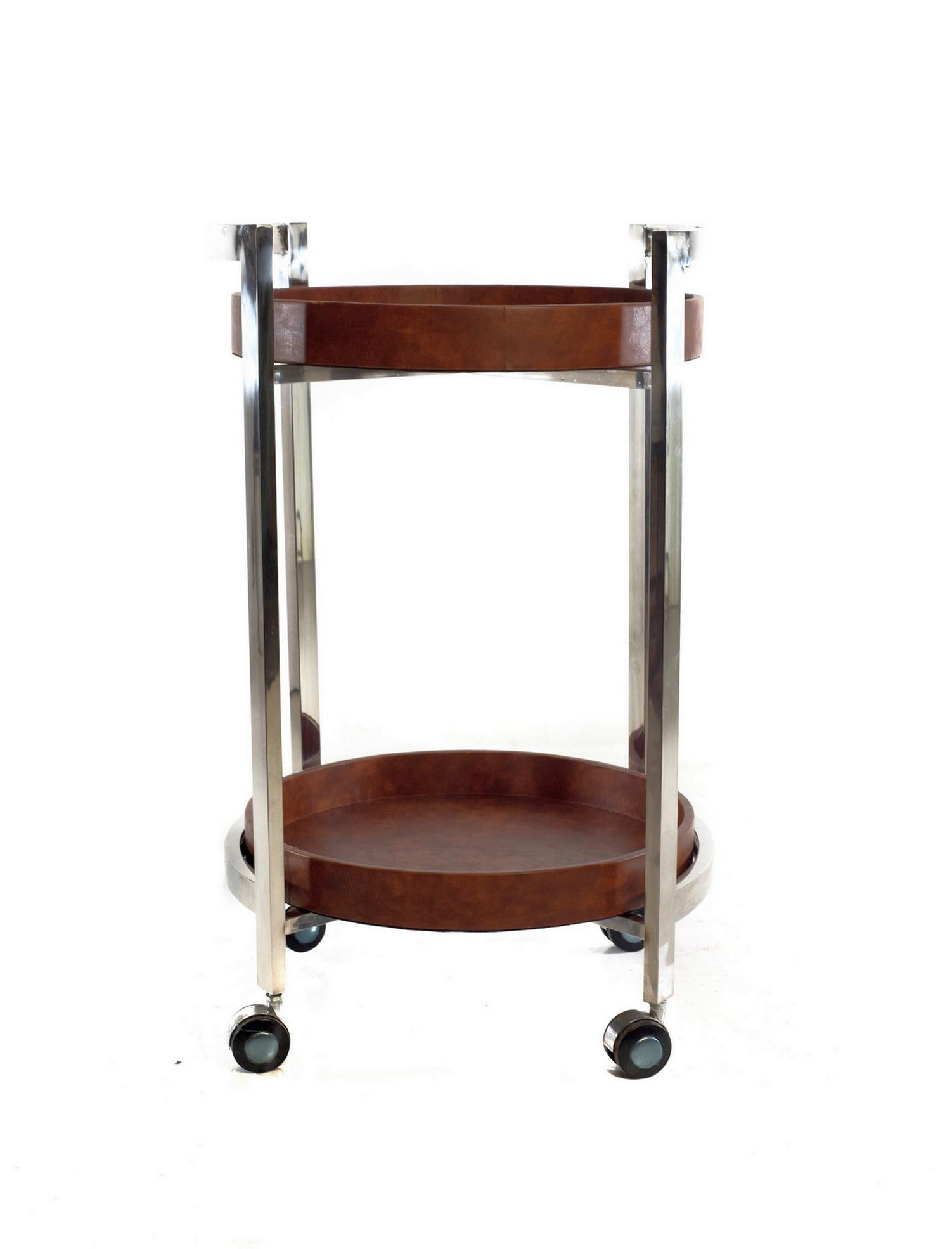 Slick Italian two tiered round bar cart from the 1970's made in chrome and faux leather. The trays are possible to lift off and use for serving as well. All original and in very nice condition.