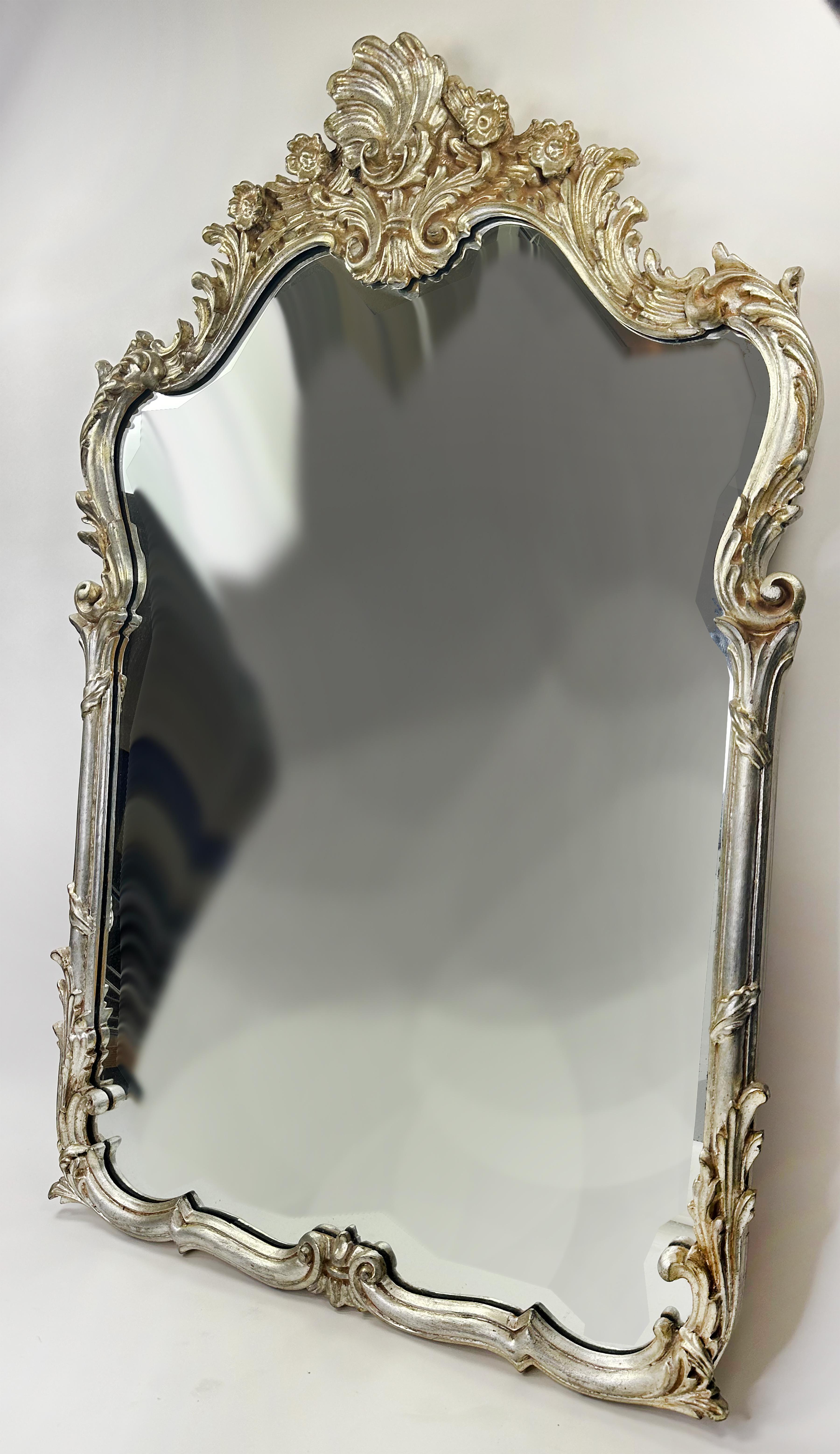 A handsome and stylish vintage Italian Baroque style mirror. Expertly hand-applied and glazed silver aluminum leaf on a wood frame hand carved by Italian artisans. The top of the mirror is ornate with floral organic shapes. The organic shapes