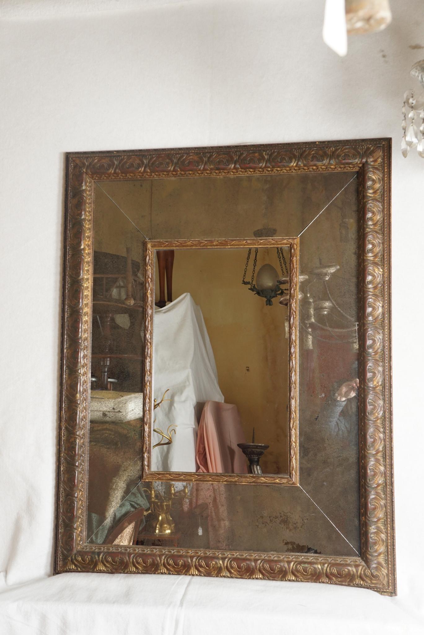 Realizzato intorno al 1950, questo specchio vintage in legno intagliato ha una superficie e uno stile antichi. La doratura fiorentina è ricca, essendo posata su un fondo rosso intenso che conferisce allo sfregamento vita e movimento. La cornice