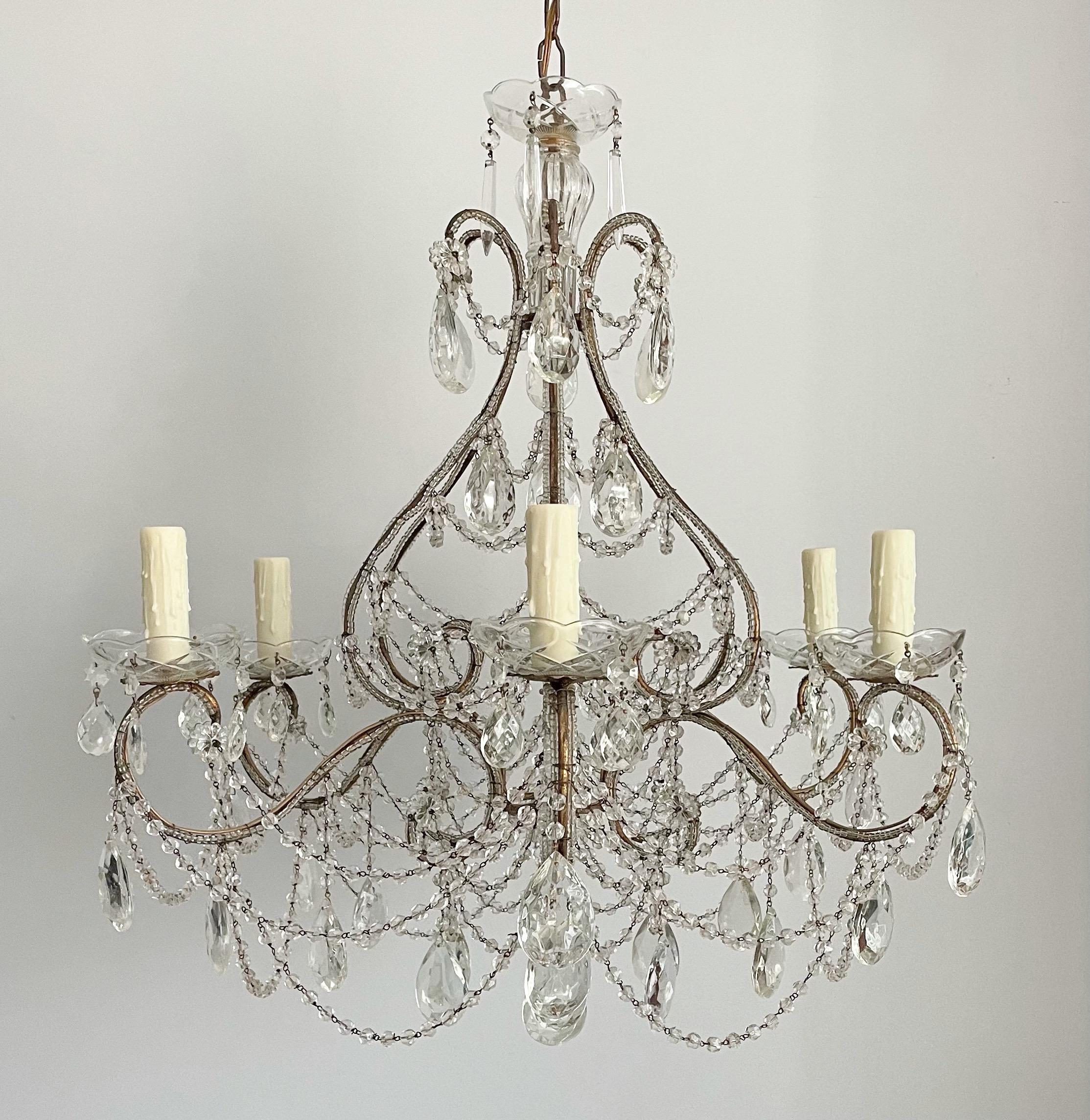 Beautiful, 1940s Italian gilt-iron and crystal beaded chandelier. 

The chandelier is defined by a graceful, scrolled iron frame with a gold-leafed finish. The frame is outlined with tiny glass beads, decorated with a bounty of “English cut” bead