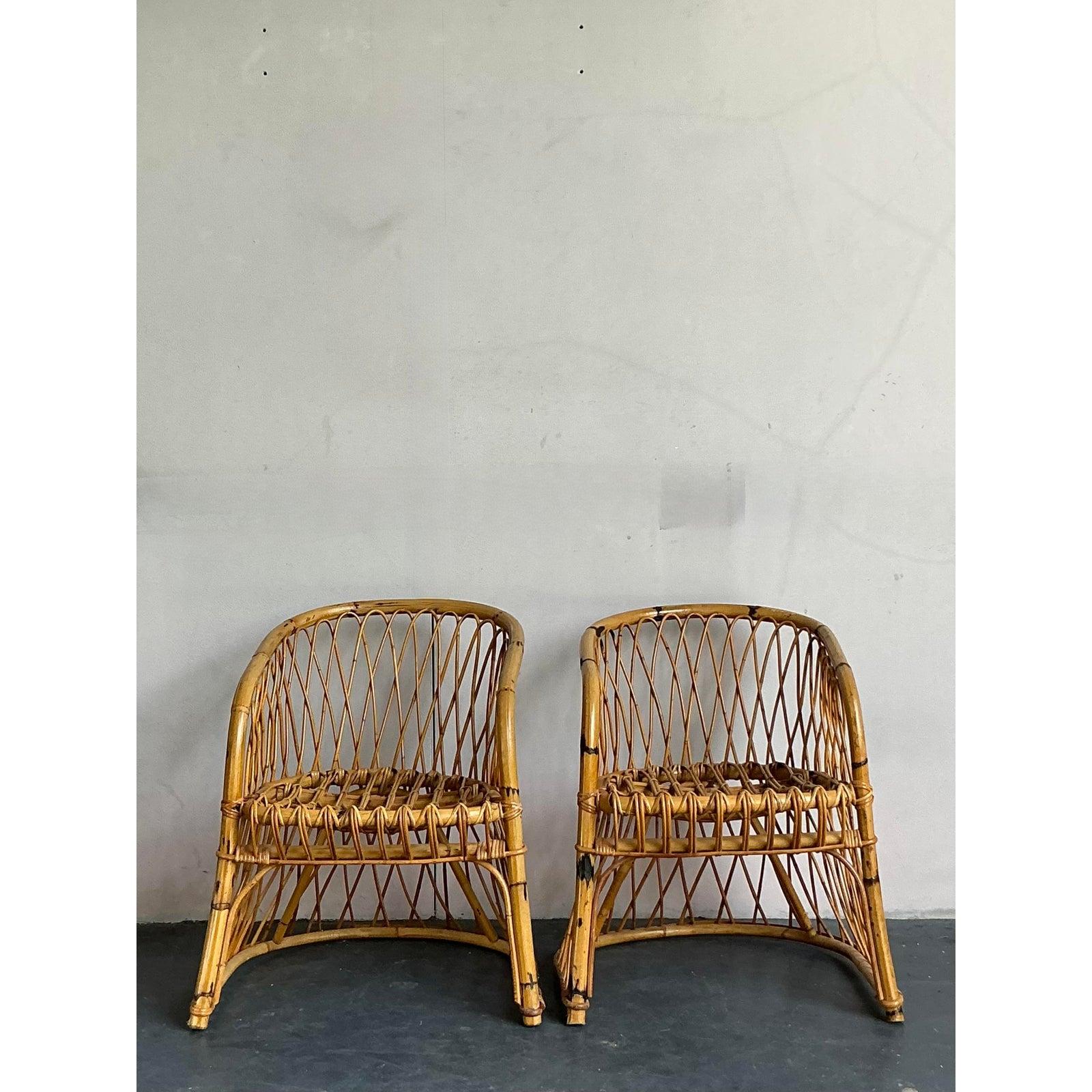 Capture the spirit of Italian Riviera chic with this delightful pair of vintage bent rattan armchairs. Exhibiting exquisite craftsmanship, each chair features a graceful, enveloping barrel-back silhouette formed from steamed and bent rattan, with an