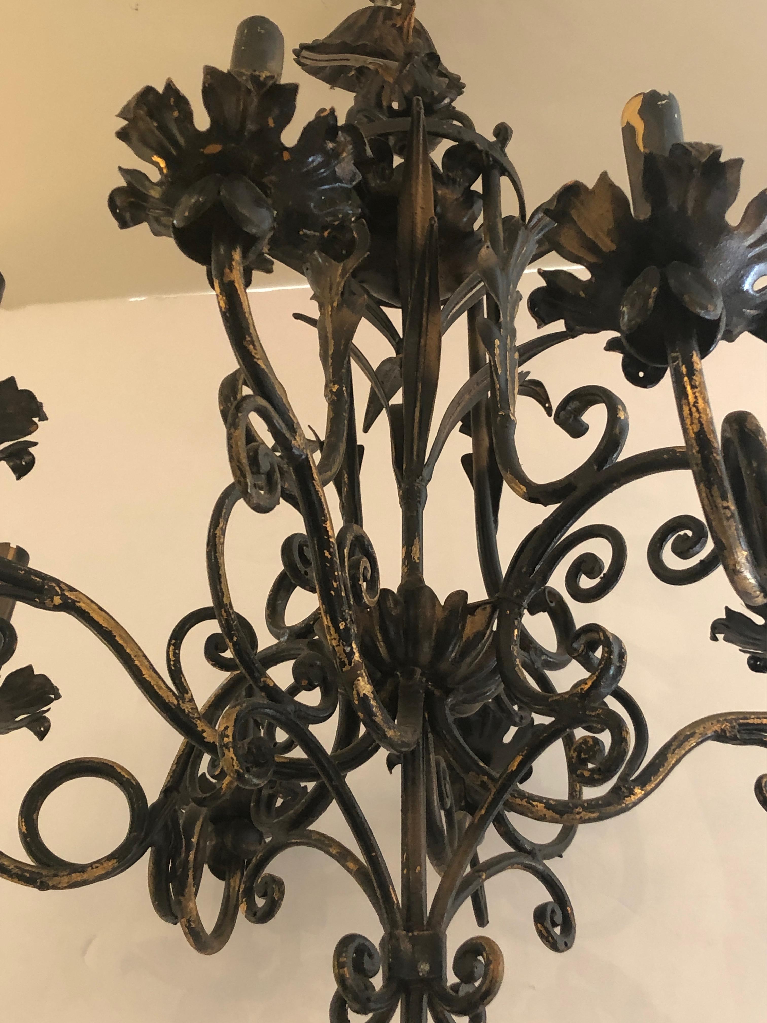 Elegant 8 arm black iron and tole Italian chandelier having handsome gilding showing through and wonderful curlicues and acanthus leaf decoration. Original ceiling cap included. 40 watts in each socket.