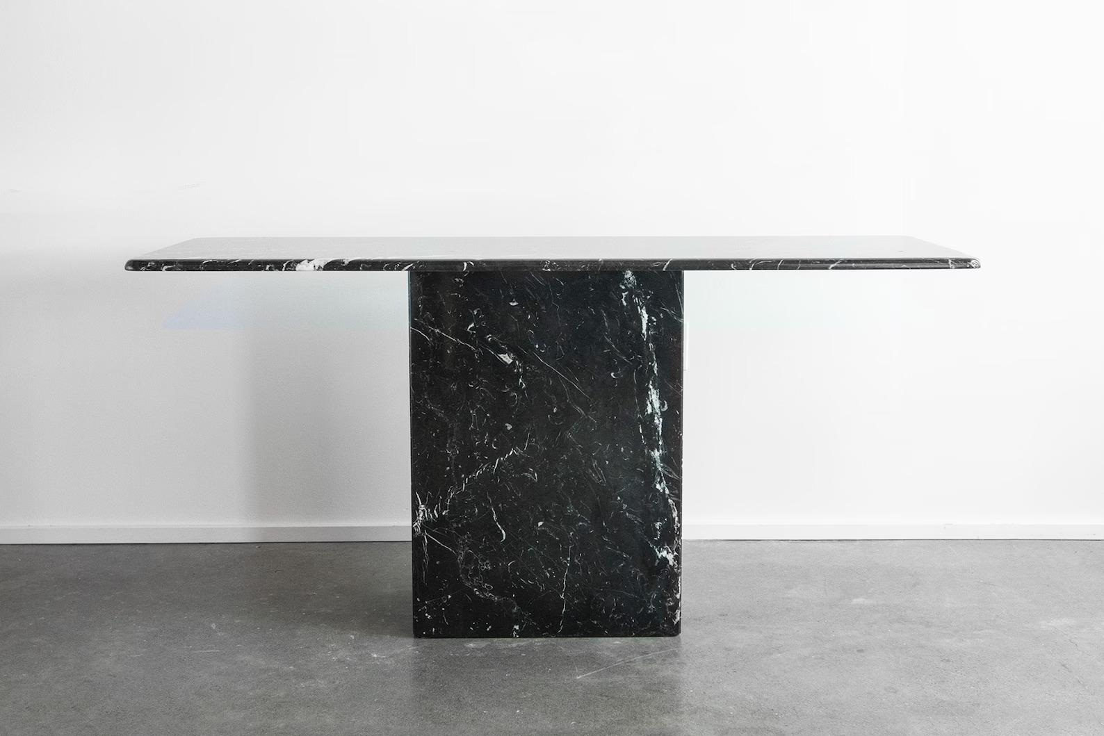 Gorgeous postmodern Italian marble console table from the 1970s. Elongated rectangle marble top sits upon a matching marble pedestal for an elegant yet modern look. Stunning white veining throughout breaks up the sleek black marble. The perfect
