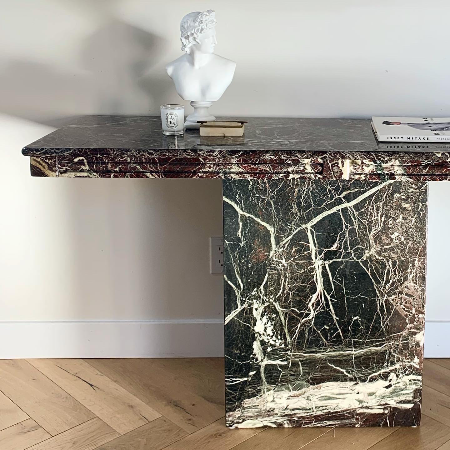 Statuesque vintage Italian marble console table in ebony with cream and and ash veining ft. undertones of burgundy. Made in Italy circa late 1970s. Pleated edge and pedestal base. Fab condition with truly minor signs of age. No losses.