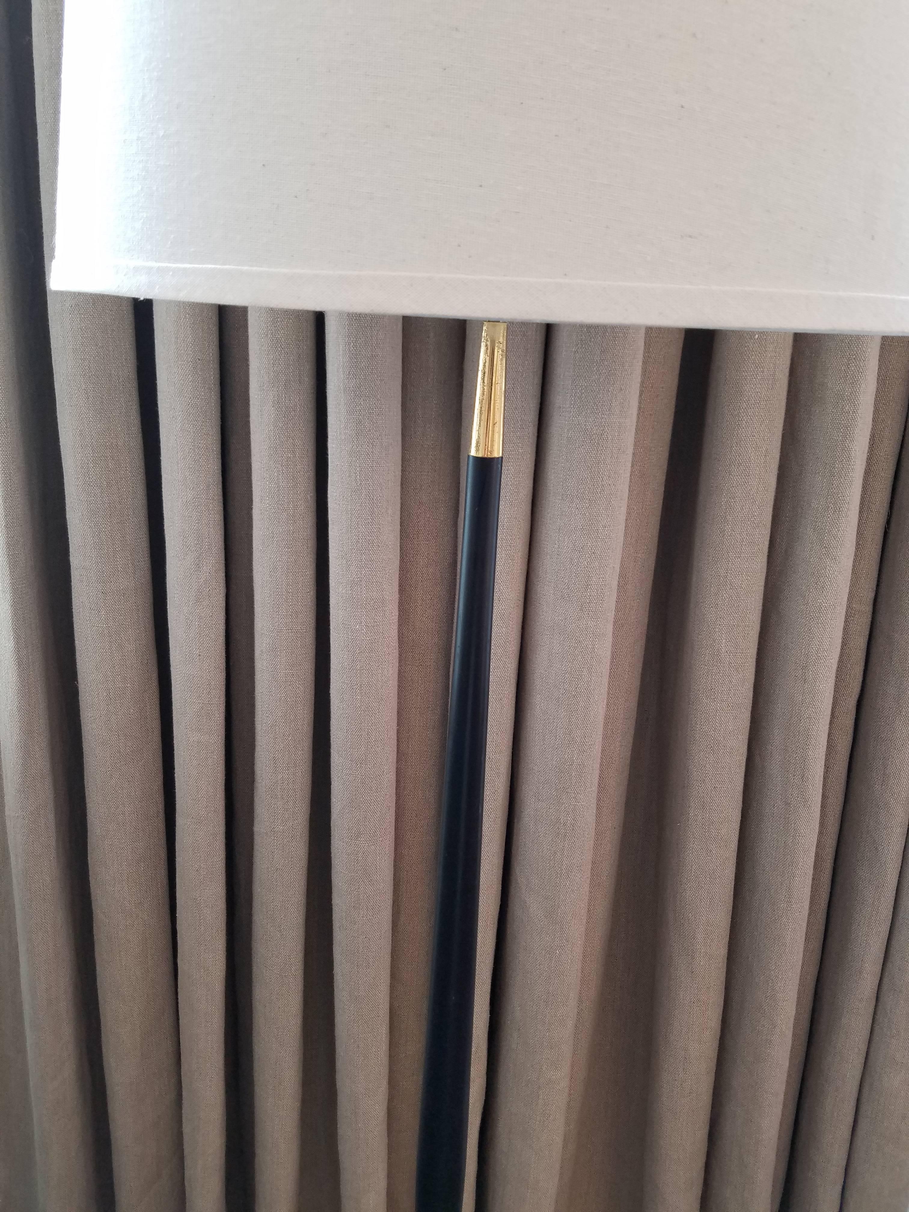 This vintage Italian floor lamp features a slender shaped black enameled pole with brass detail at top and is supported by a brass three foot raised base. Elegant midcentury piece has been re-wired but not re-furbished. Overall height to top of harp