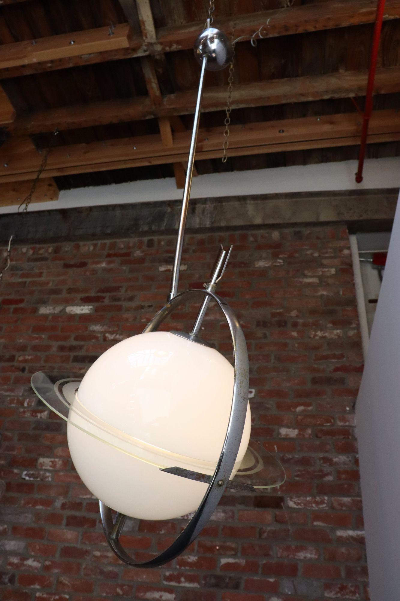 Pendente a forma di Saturno planetario modernista italiano di Gio Ponti e Pietro Chiesa per S. A. Luigi Fontana & Co. (1930 ca.). Composto da un globo centrale in vetro blu pallido trafitto da una freccia in metallo con un disco in vetro inciso che