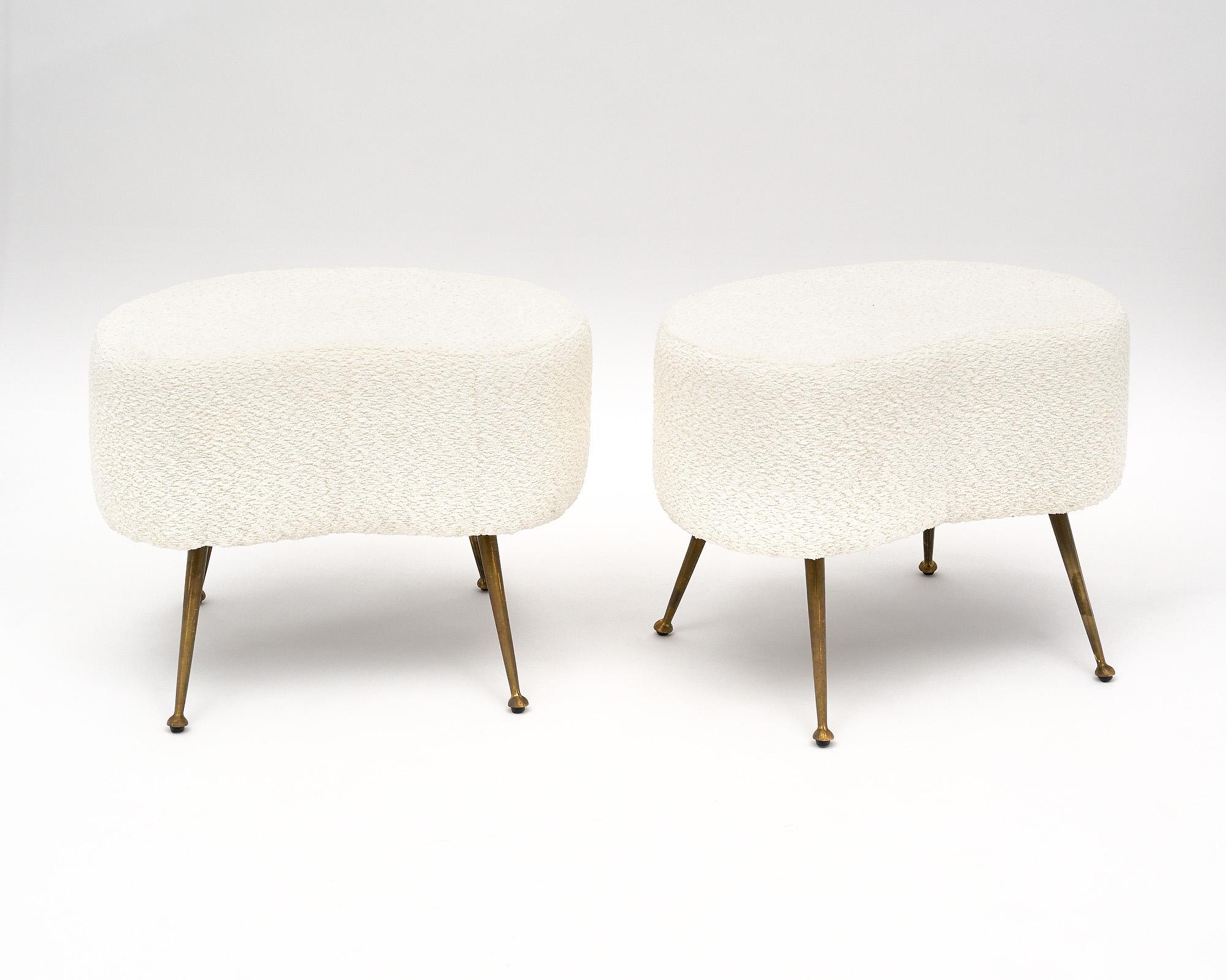 Pair of Italian vintage benches or stools with flaring brass legs. We love the quirky shape of the seats and the striking lines of the mid-century design. They have been newly upholstered in a wool blend boucle fabric in a white color.
