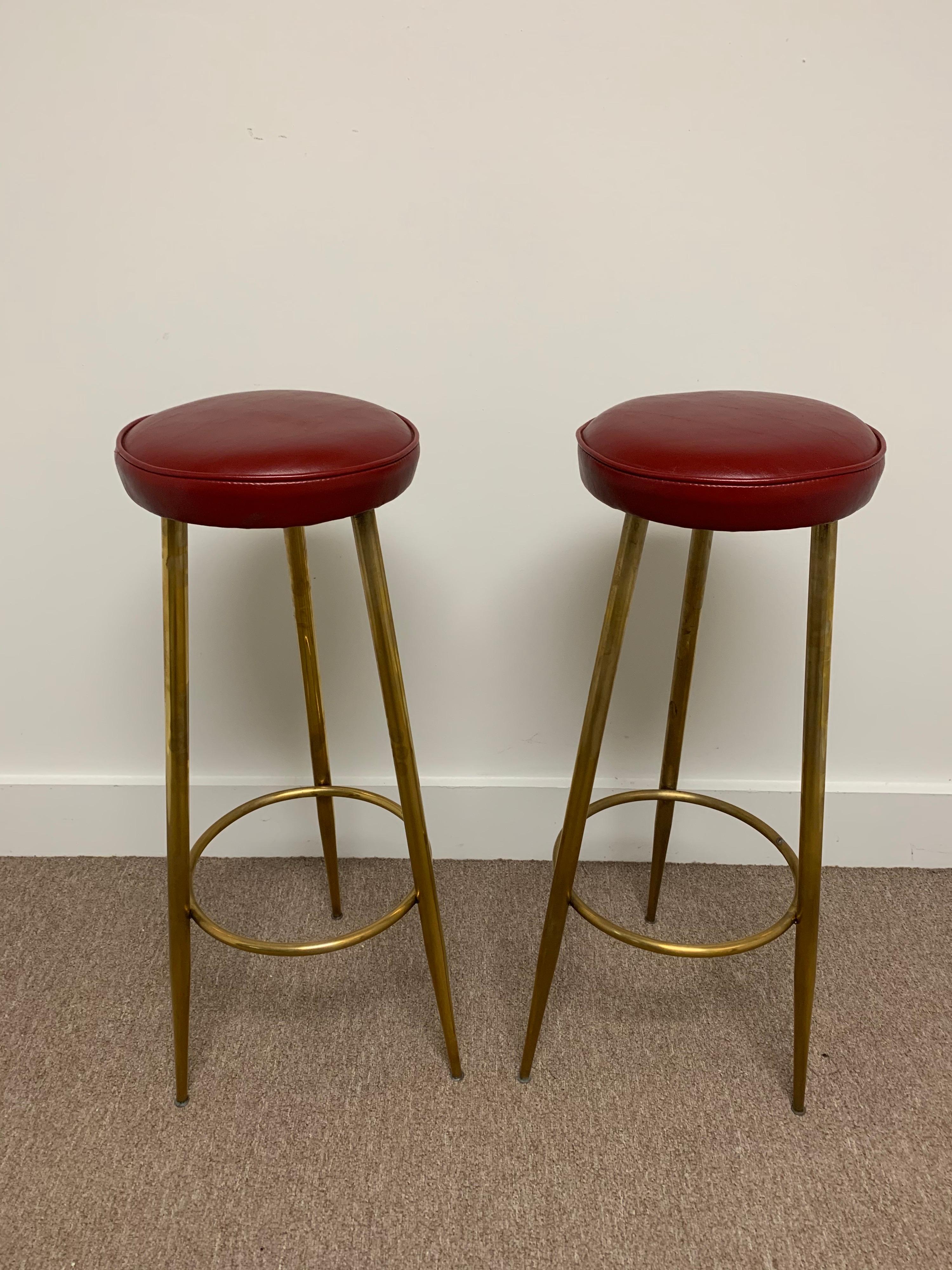 These bar height vintage Italian brass stools have the original red vinyl seats. The brass has a lovely age and patina. The brass footrest is a classic design element of Italian designs.