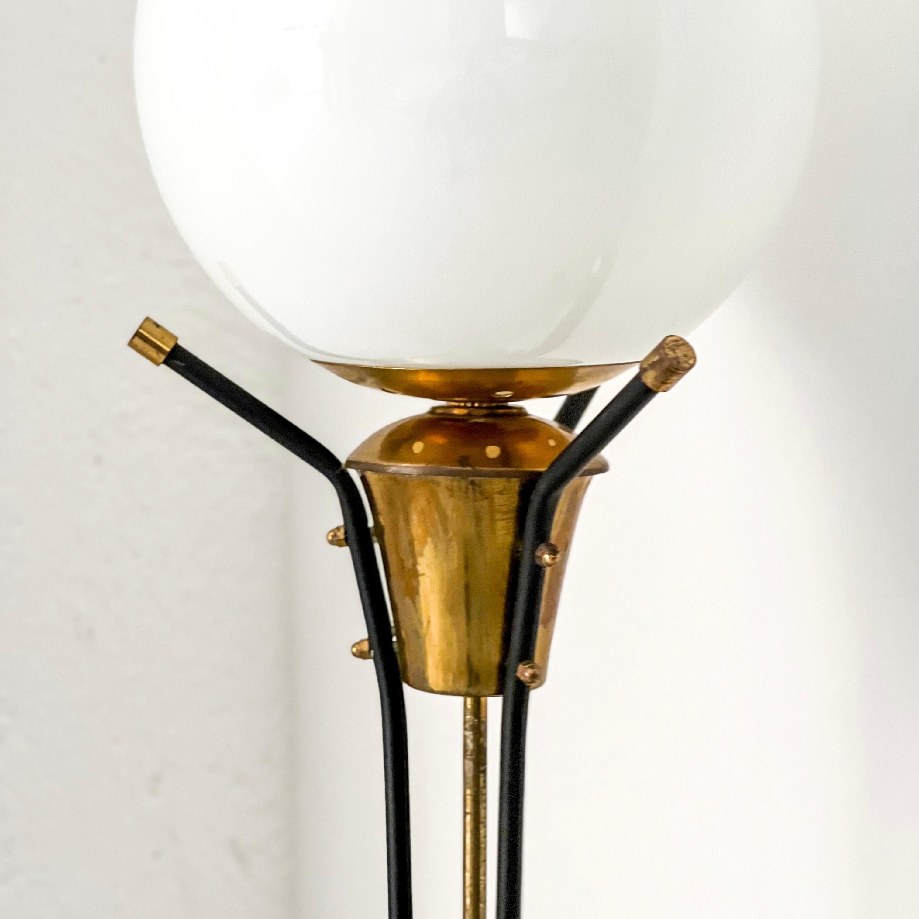 Offered for sale here is a beautiful, rare and well preserved floor lamp, produced in Italy and dating back to the 1950s. It is a floor lamp of medium height, with a thin base consisting of three elegant brass legs. On top of the legs, three brass