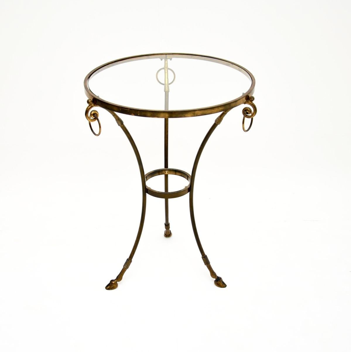 Impresionante mesa auxiliar gueridón italiana vintage de latón, de alrededor de la década de 1960.

Es de una calidad excepcional, la parte superior circular tiene tres anillos en los lados, se alza sobre una base trípode con patas de cascos. Está
