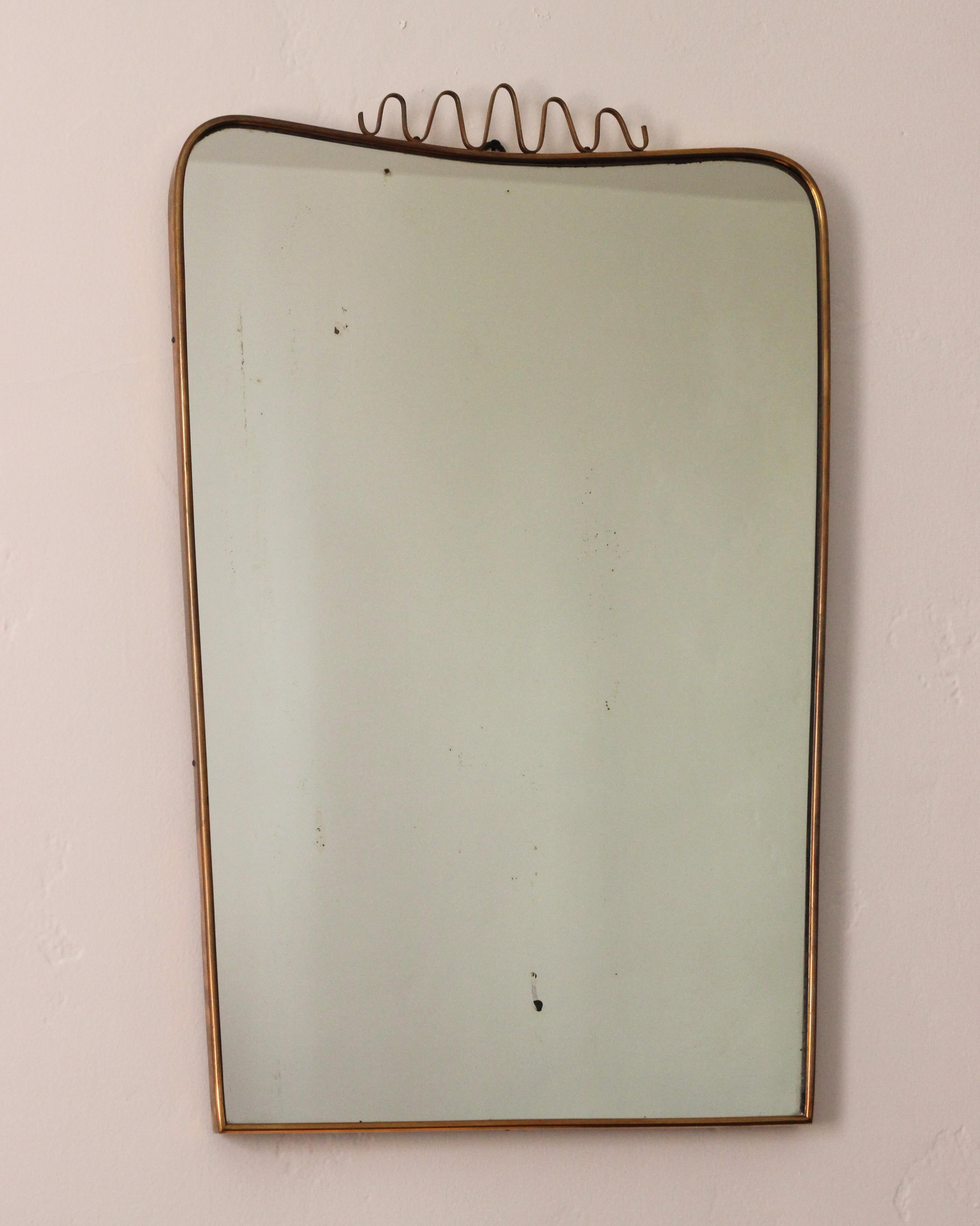 Italian wall mirror, produced in Italy, 1960s. Organically cut mirror glass is framed brass and shows patina. 

Other designers of the period include Gio Ponti, Fontana Arte, Max Ingrand, Franco Albini, and Josef Frank.