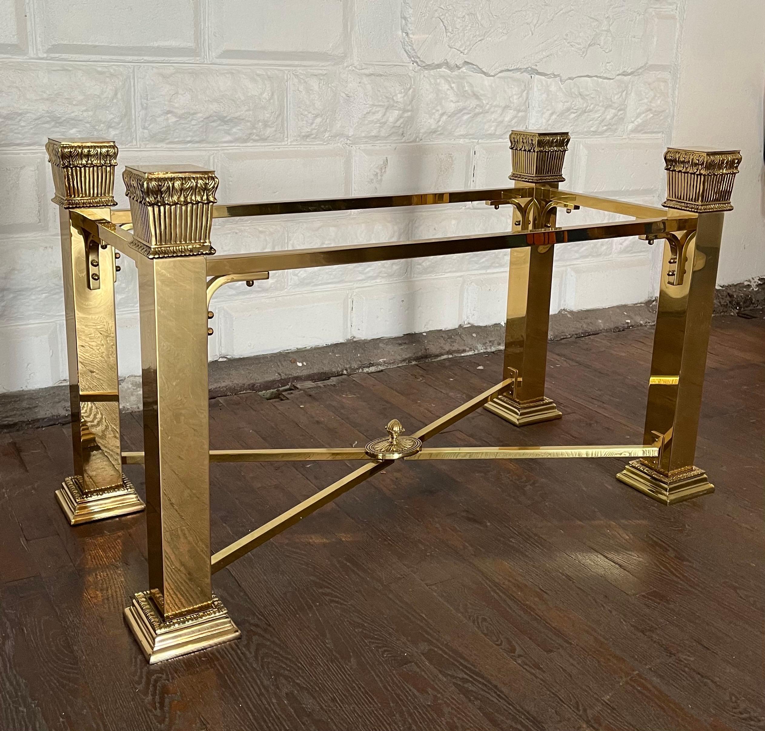 Magnifique table de salle à manger néoclassique en laiton italien à la manière de Mastercraft. Les quatre colonnes carrées avec feuilles d'acanthe et les traverses avec fleuron central sont d'une grande profondeur. 
Une pièce vraiment étonnante.
En