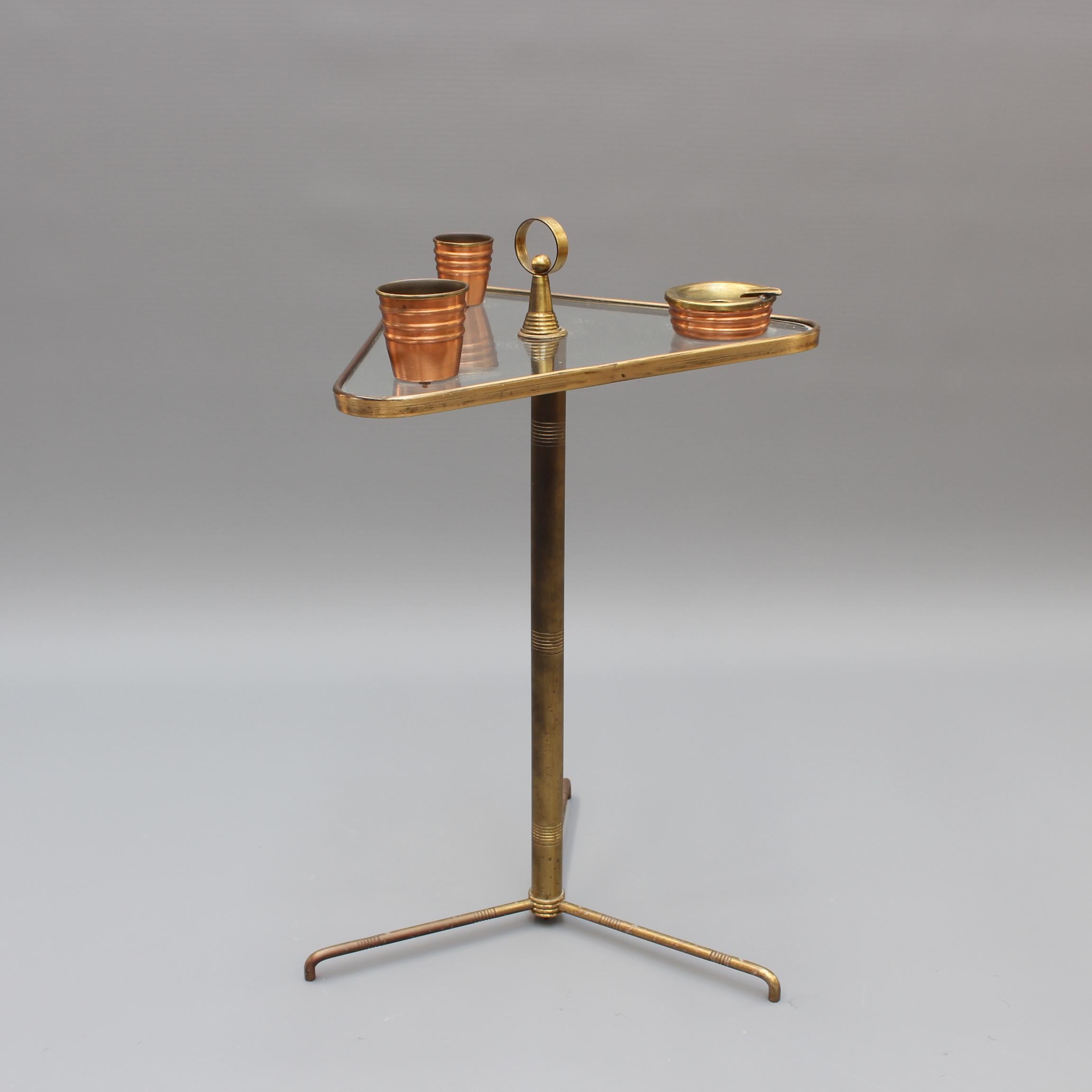 Rare, vintage Italian brass smoking tableside stand with glass top (circa 1950s). Distinctive, charming stand with cigarette and match receptacles with ashtray on a stylish, three-legged brass support with art deco features and glass top. Probably