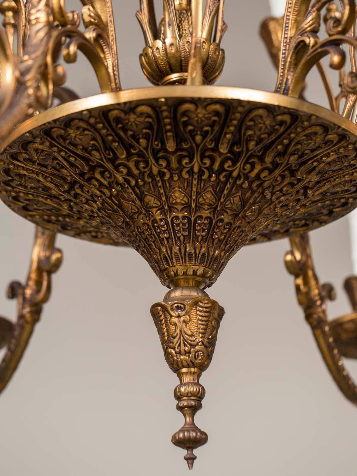 A vintage Italian Art Nouveau bronze two-tier chandelier having twelve lights from Italy, circa 1920. Notice the elongated silhouette of this Italian light fixture with six lights in the upper level and six lights in the lower level all arranged