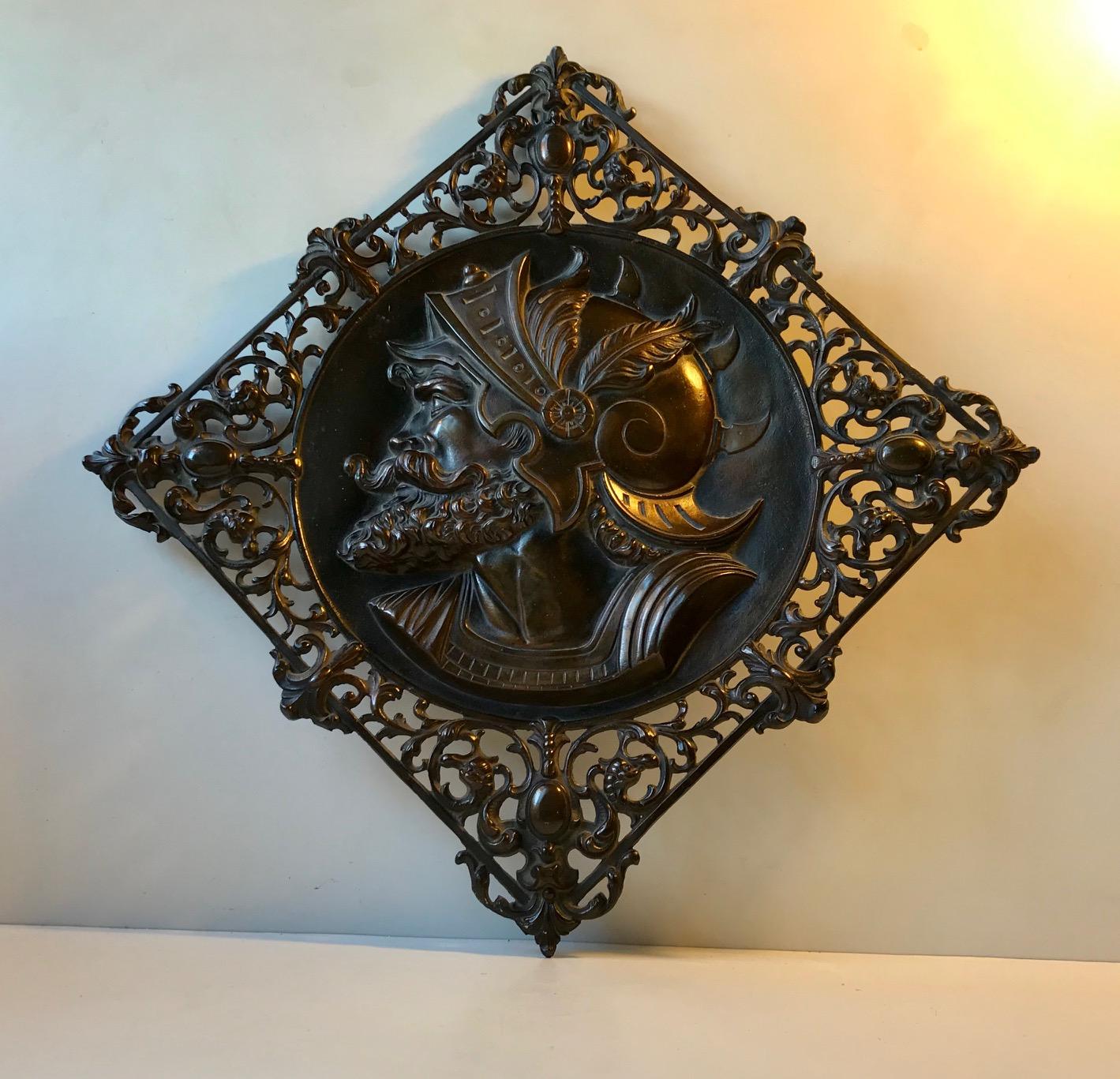 Whether this bronze wall plaque depicts a Roman Gladiator or Legionaire is uncertain. It was brought home from Rome in 1970 or 71. It is made from solid bronze that has a rich brown patina. The detailed ornamentation is partially perforated. It has