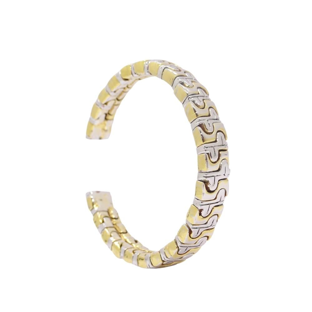 Beautiful rigid bracelet or high-end costume jewelry bracelet that combines gold and silver tones. The structure is semi-open, composed of a succession of articulated links with an alternation of relief details that generates an interesting visual