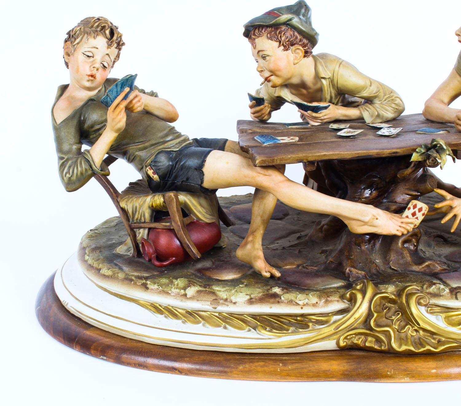 This is a large impressive vintage Italian Capodimonte porcelain figural group sculpture of, 'The Card Cheats' by Bruno Merli, late 20th Century in date.

The expertly sculpted figures of boys cheating while playing cards on a tree stump on a