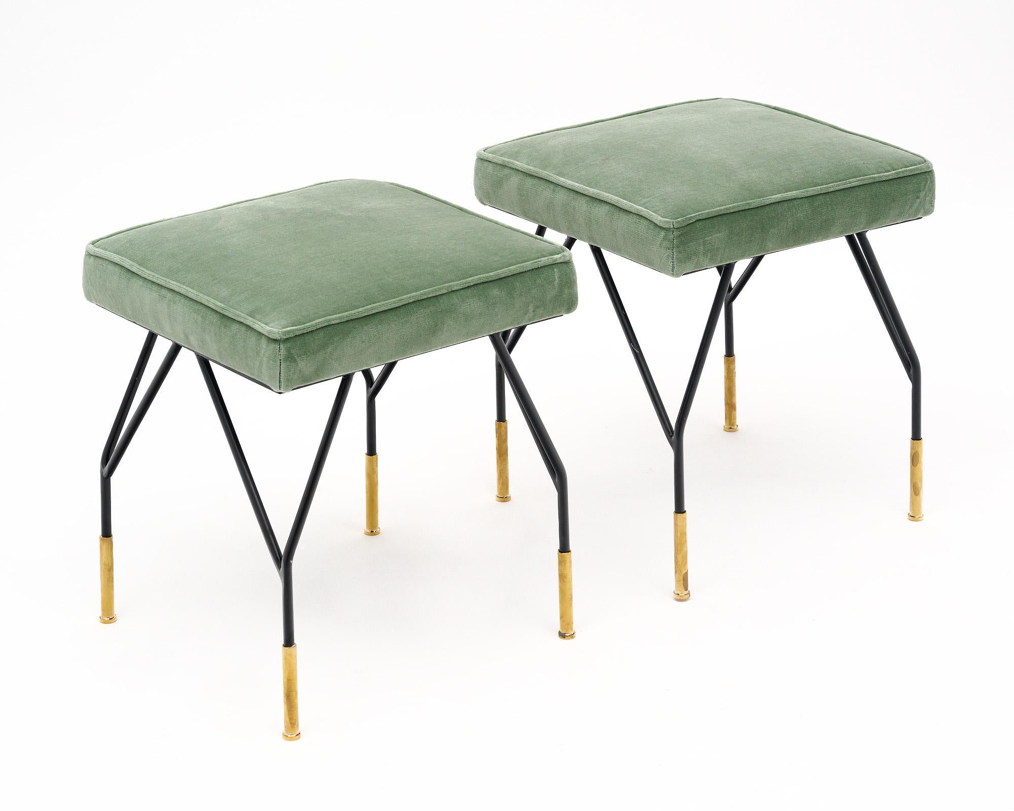 Pair of Italian stools in the style of designer Carlo di Carli. The pair features the black lacquered steel bases with gilt brass feet that are iconic of the designer. They are upholstered in a new sage green velvet fabric.
