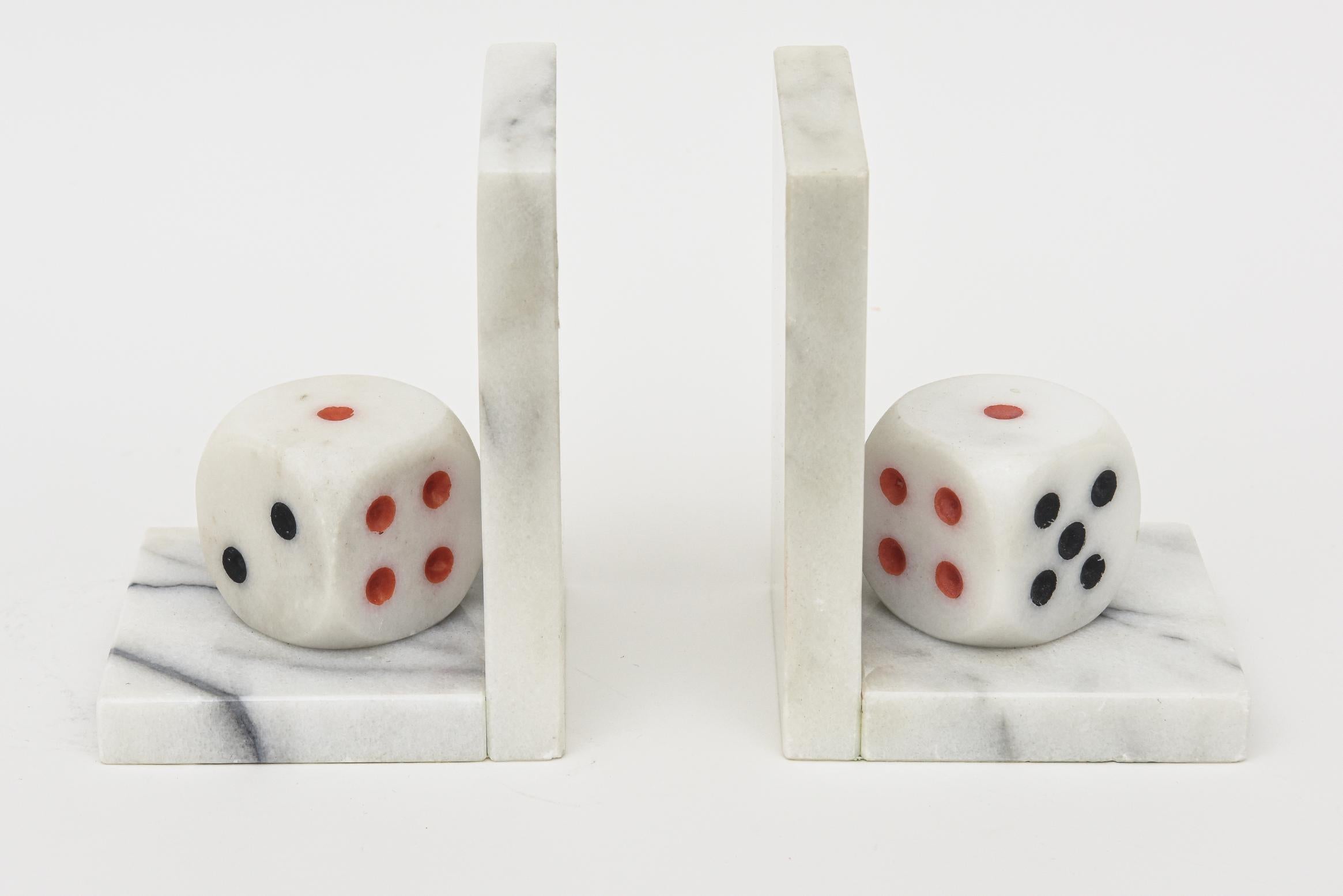 This pair of vintage unusual Italian 1960s white carrara marble bookends have large dice propped as the focal point with red and black resin dots. They have been professionally polished to the best they can be now. The original worn felt is still