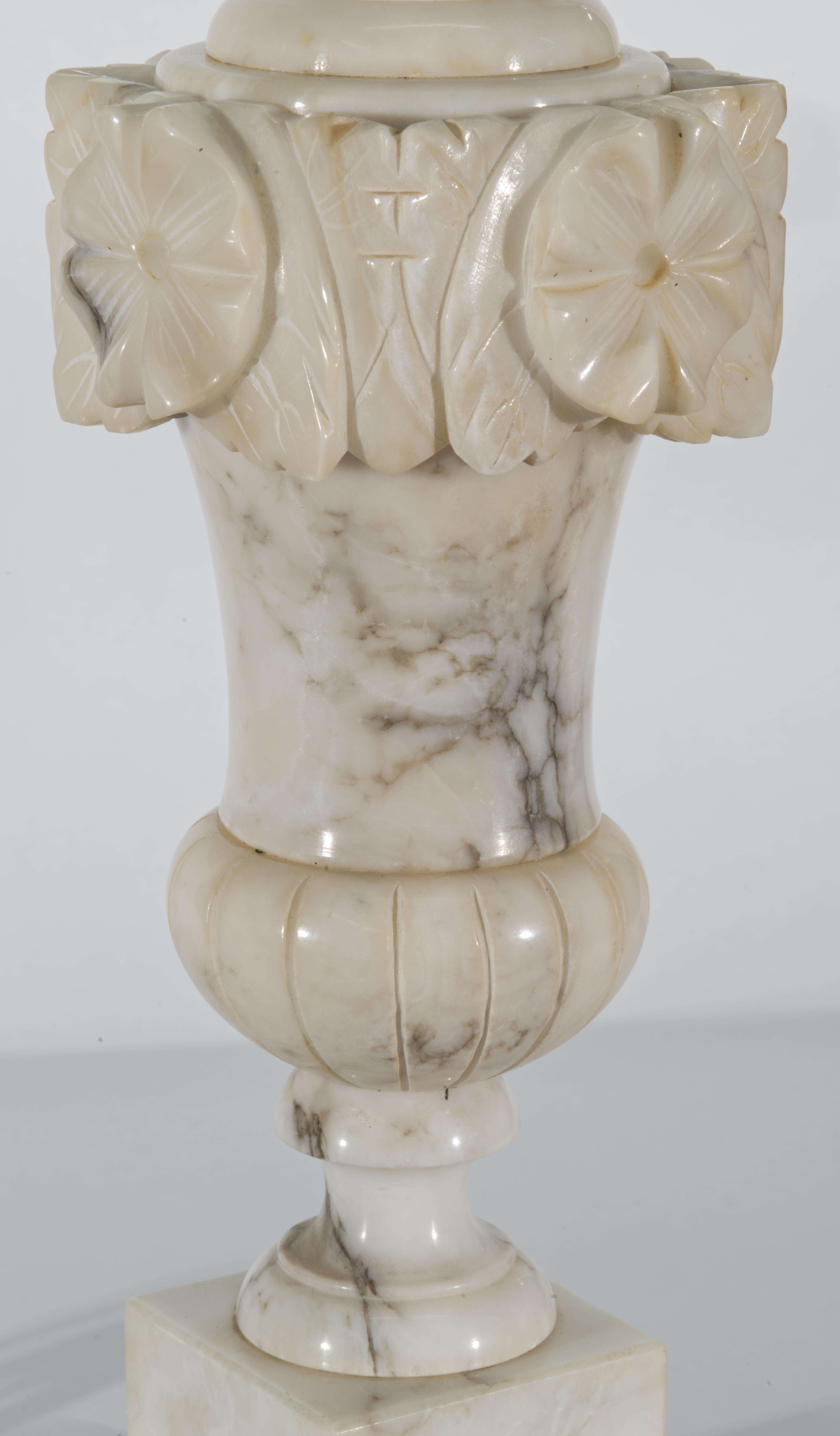 Vintage Italian handgeschnitzte Alabaster Tischlampe mit Baluster Urne Form mit einem Kranz von Blumen und Blätter akzentuieren die Spitze der Urne. Der Lampenkörper ist auf einem abgestuften quadratischen Alabastersockel montiert; die Lampe ist mit