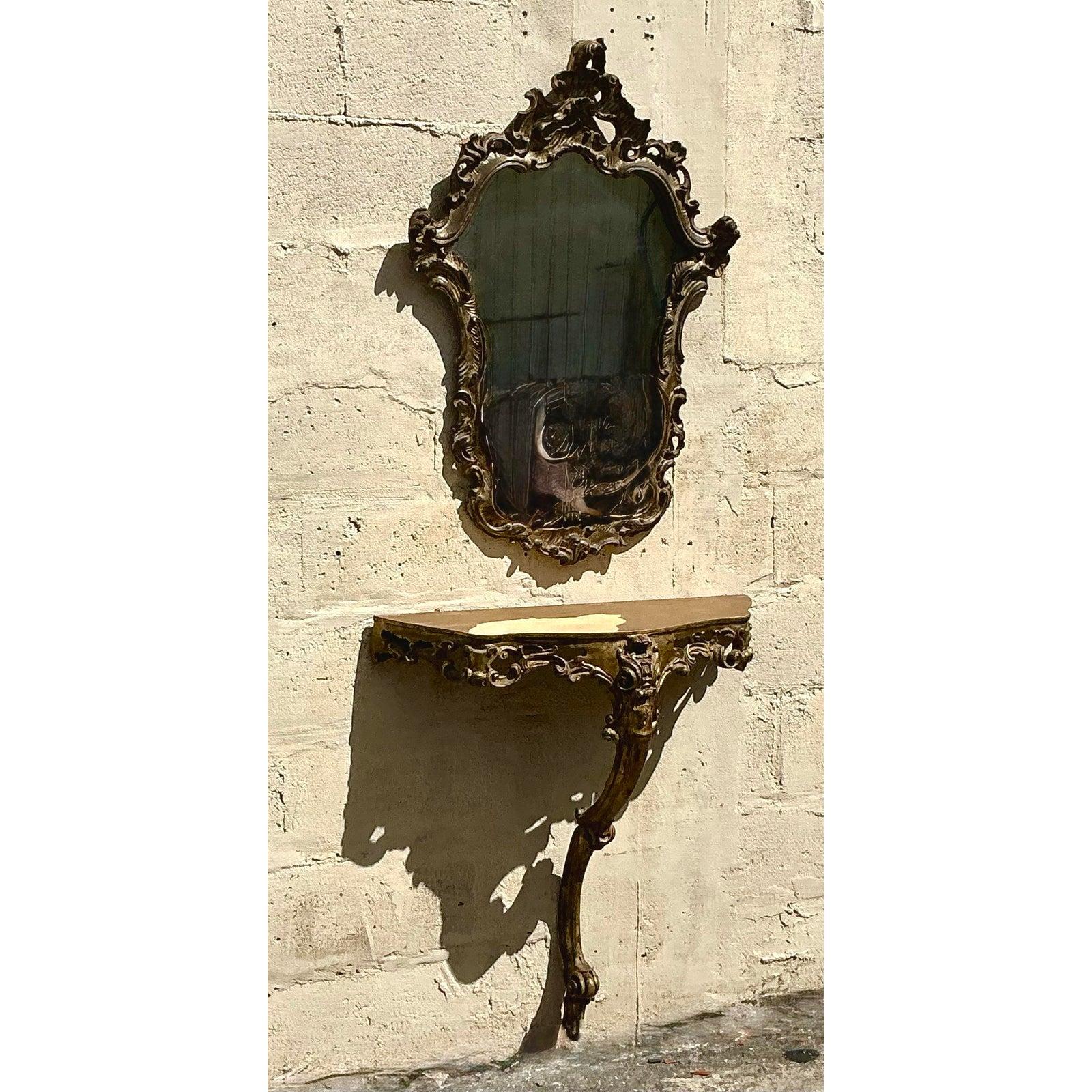 Questo raffinato set vintage italiano è composto da uno specchio dorato ornato e da una consolle demilune abbinata, che incarna l'eleganza senza tempo dello stile revival rococò. Lo specchio presenta un'elaborata cornice a spirale con intricati