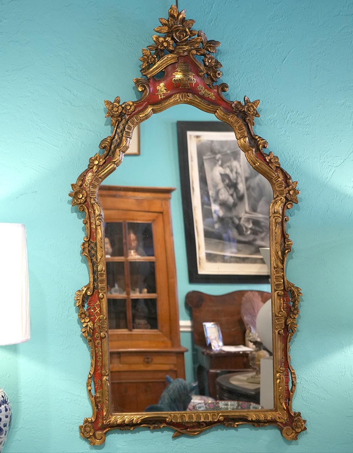 This is a magnifiscent giltwood wall mirror carved in the Rococo style and featuring red painted cartouches decorated with gilt chinoiserie themes. These mostly red areas with their gilt decorations greatly add to the overall attractivenes. The