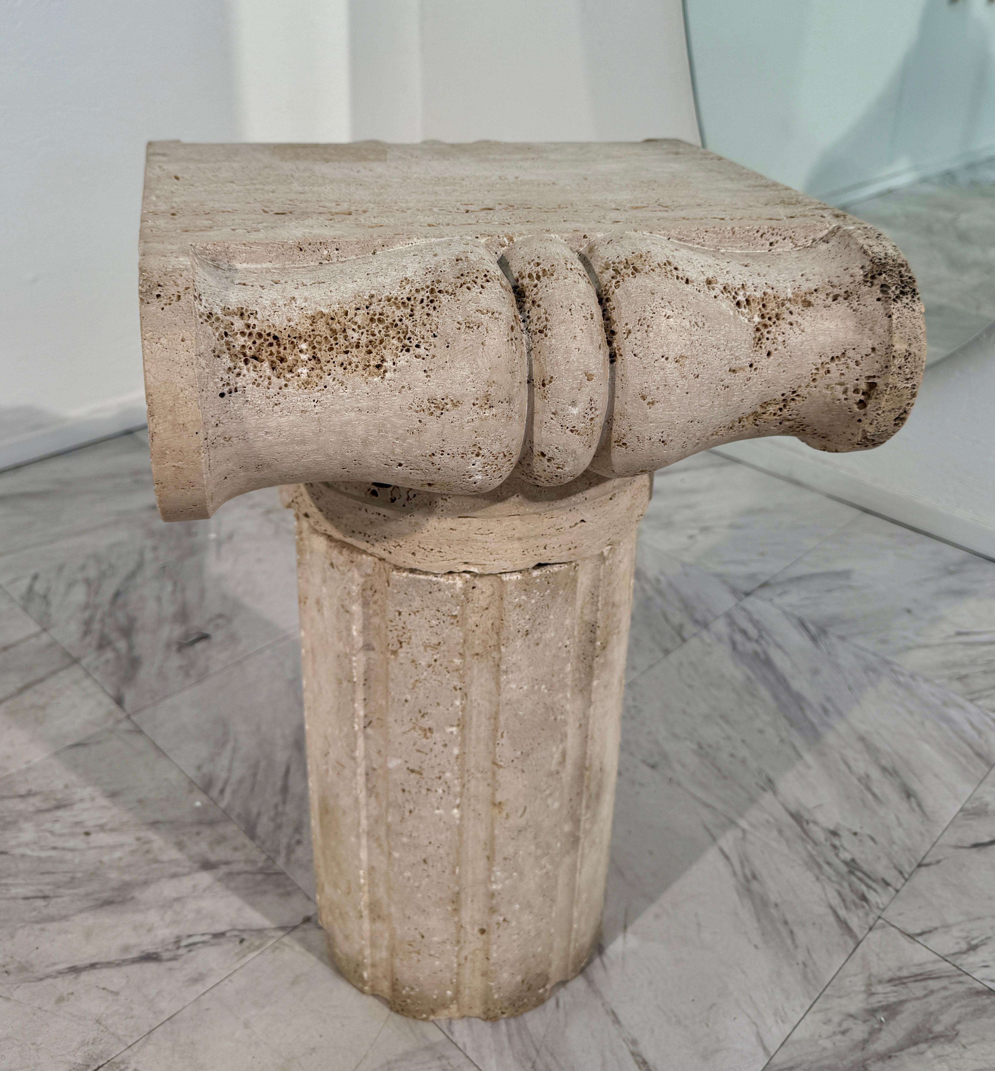 Un piédestal vintage sculptural en pierre naturelle de travertin, conçu sous la forme d'un chapiteau de colonne classique. La pièce présente une texture riche, des veines organiques et une patine subtile qui soulignent la beauté intemporelle du