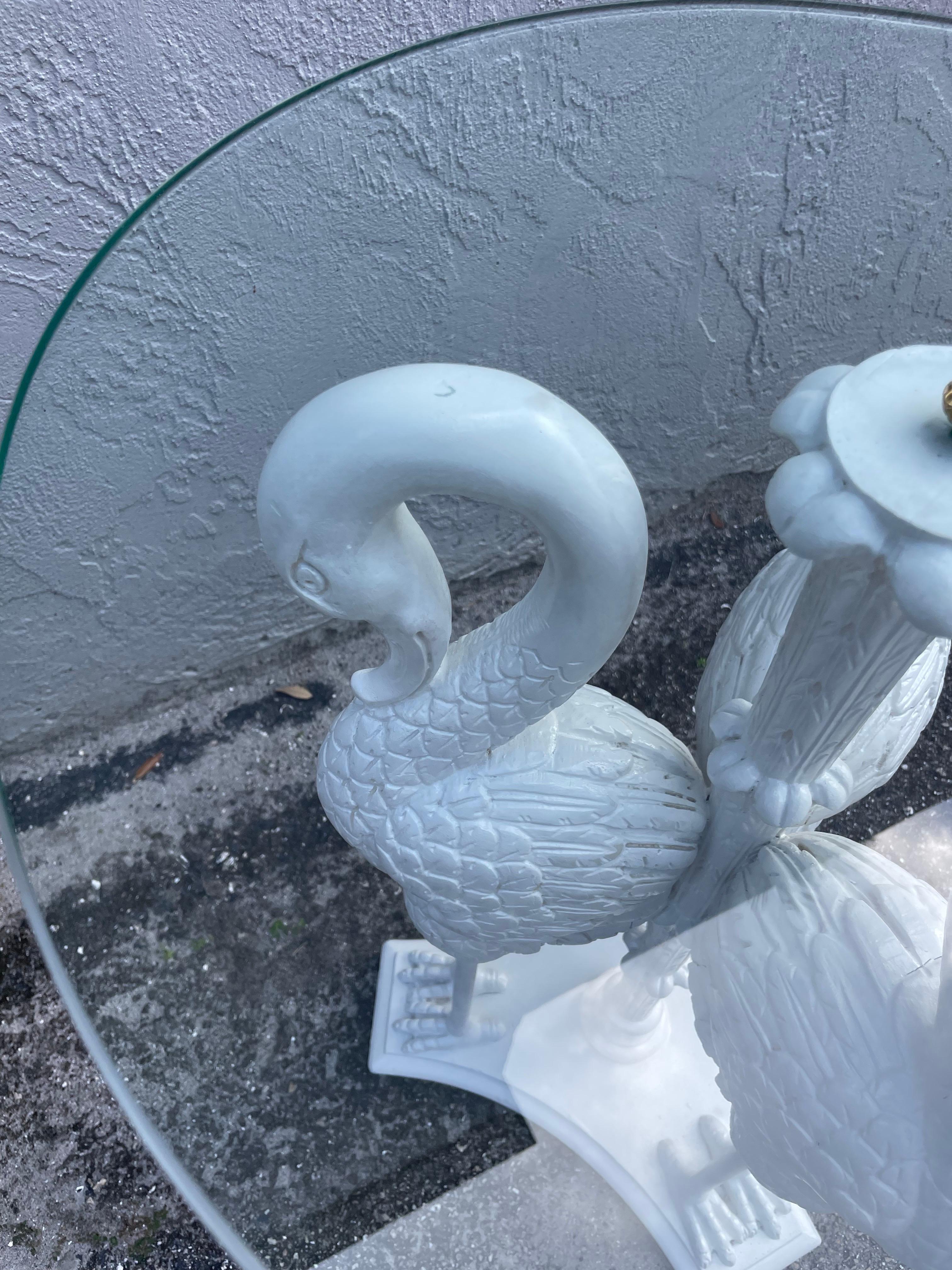 Splendido tavolino a tre cigni intagliato e dipinto con piano in vetro rotondo da 20 pollici. Tre sculture di cigno intagliate a mano che sorreggono un piano in vetro con un disegno floreale al centro e un terminale in ottone sulla parte superiore.