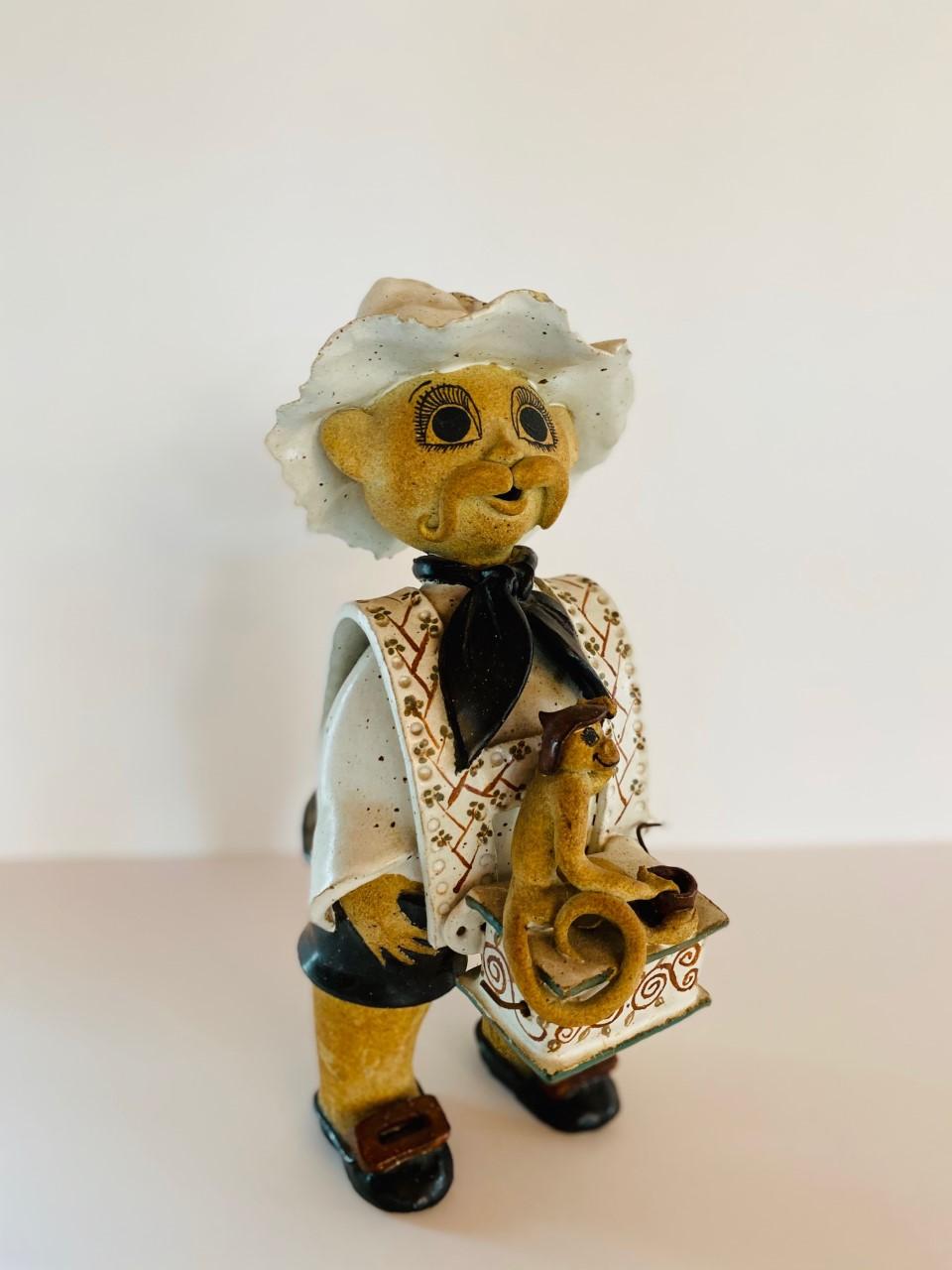 Beautifully rendered ceramic figure of man with musical grinding box and monkey. The detail and execution of this ceramic piece, made by hand is outstanding. The figure renders details (feather in hat, buttons in the back, and monkey figure
