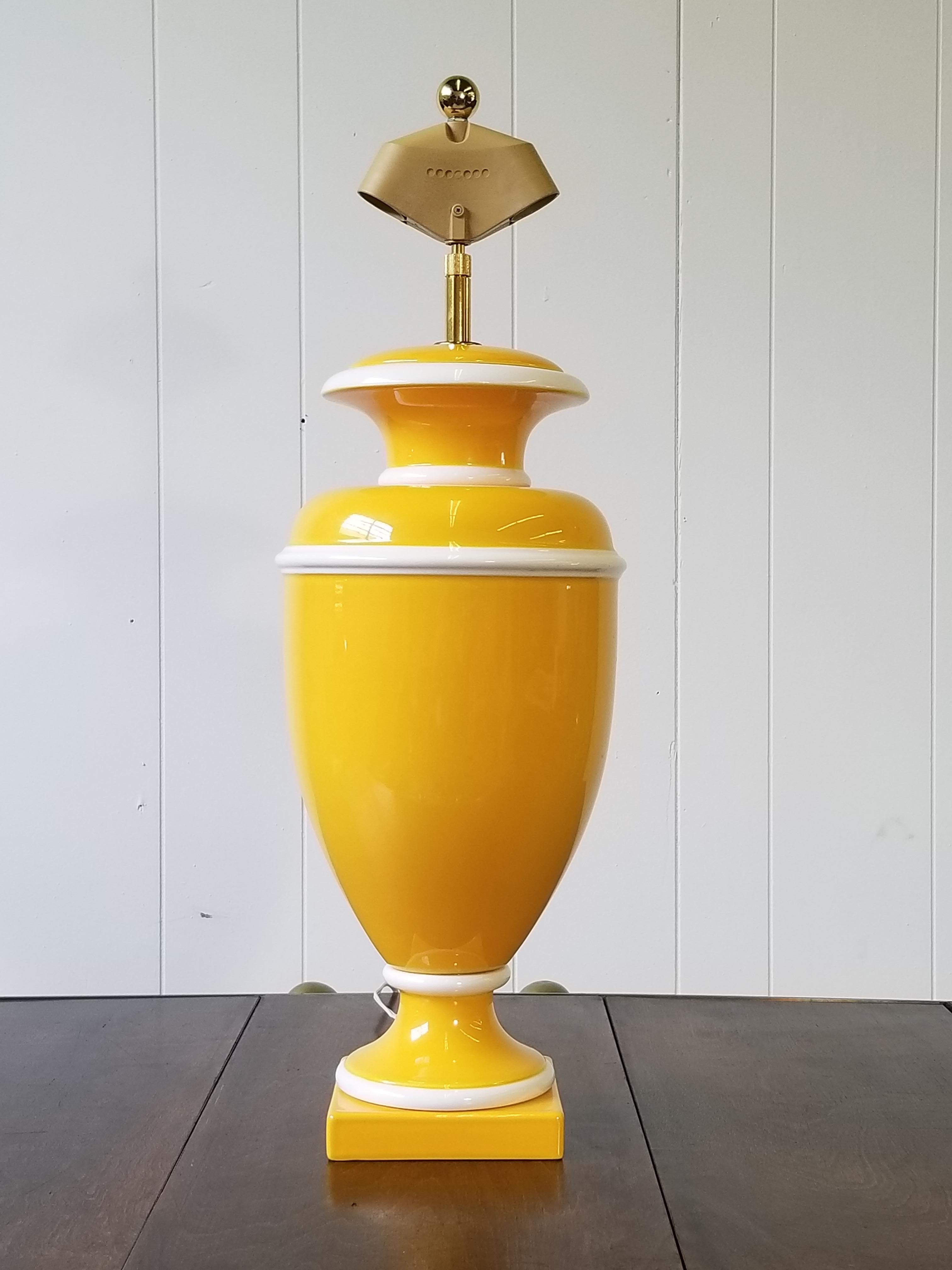 Dramatic Hollywood Regency Italian ceramic urn lamp in bright yellow and trimmed in white. There is a built in and adjustable harp plated in gold; it fully extends to 38