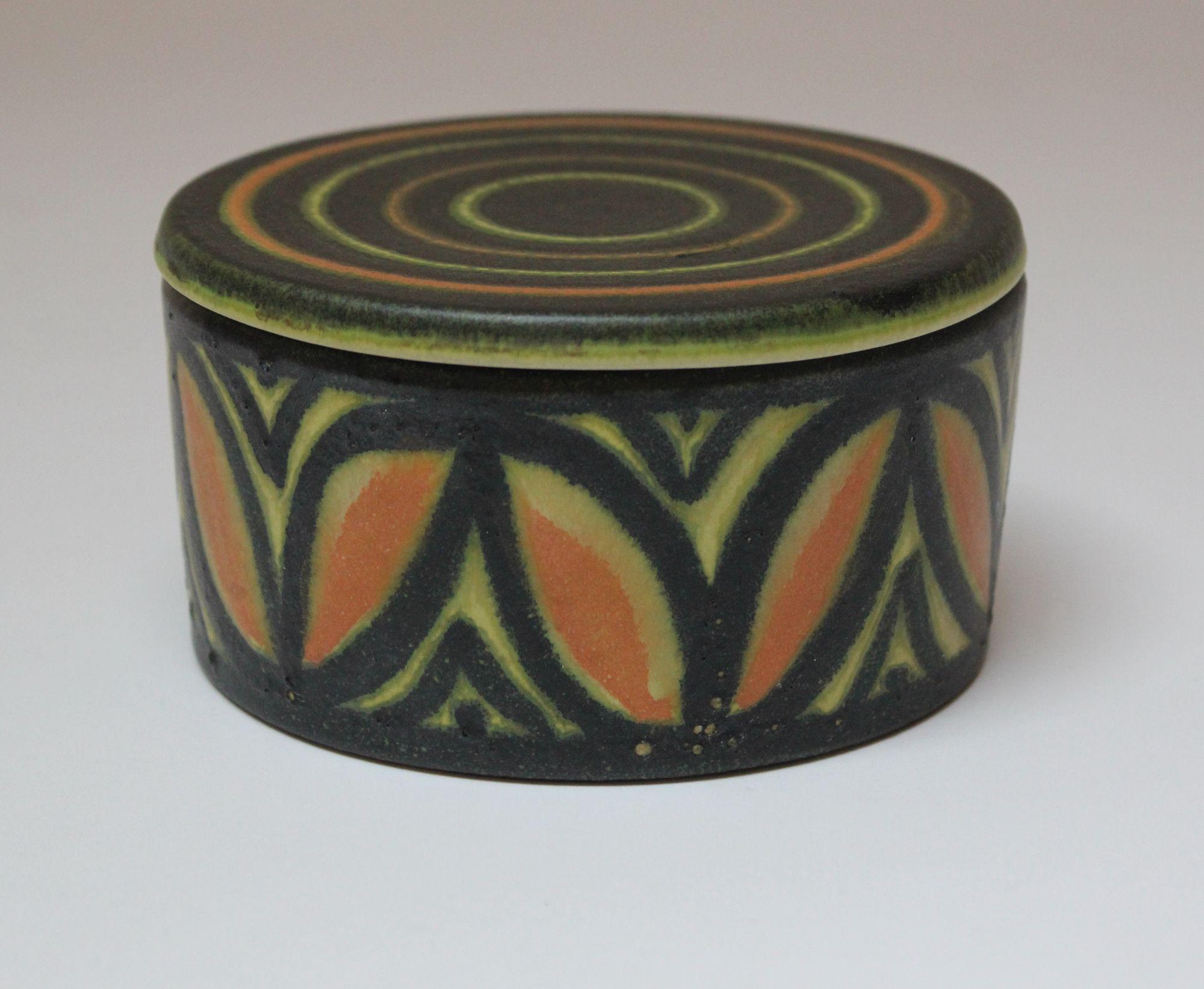 Boîte ronde / pot à couvercle en céramique avec motif de cercles concentriques et de pétales par Raymor (vers les années 1960, Italie).
Palette et design attrayants en excellent état.
Non signée.
H : 2.63