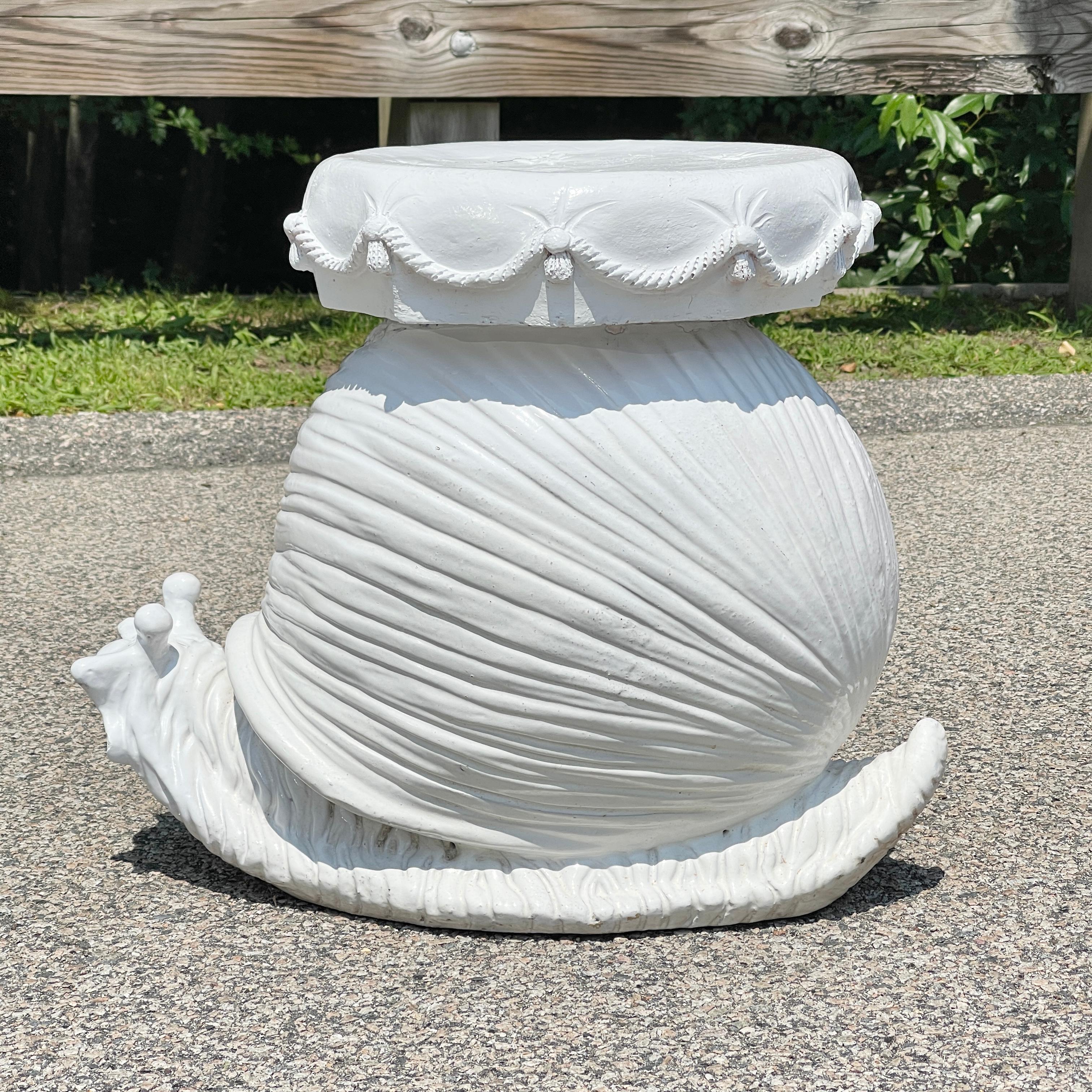 Enchanting white enamel glazed terracotta stool or side table in the form of a snail curiously looking out from its stylized shell and having a faux button tufted cushion seat embellished with braided rope and tassels. Imported from Italy during the