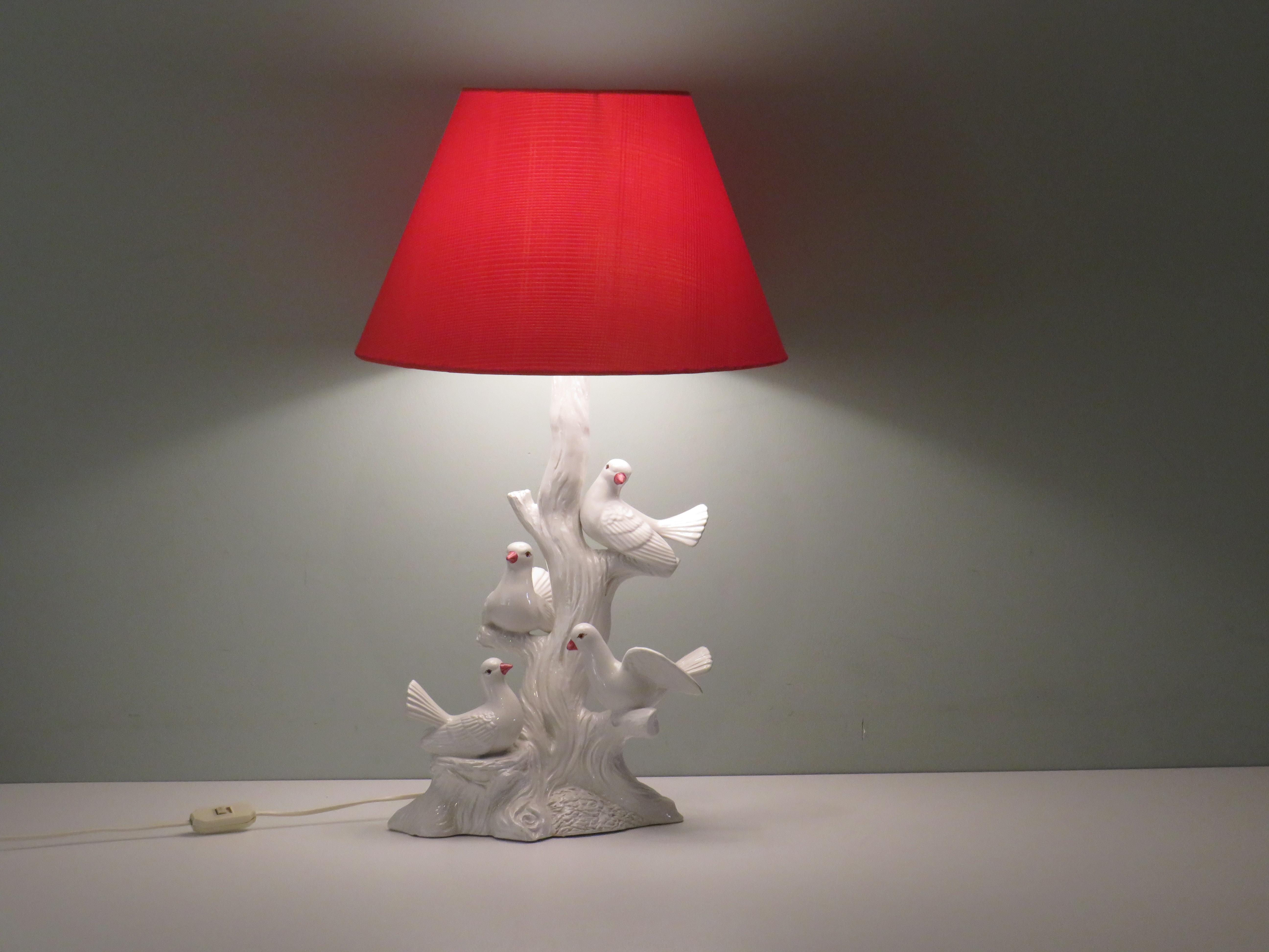 The lamp has a white glazed ceramic base with 4 doves on a branch and is fitted with a custom tangerine silky lampshade. It is equipped with an E 27 fitting and white cord with an on and off button.
The height of the lamp base is 46 cm, the width