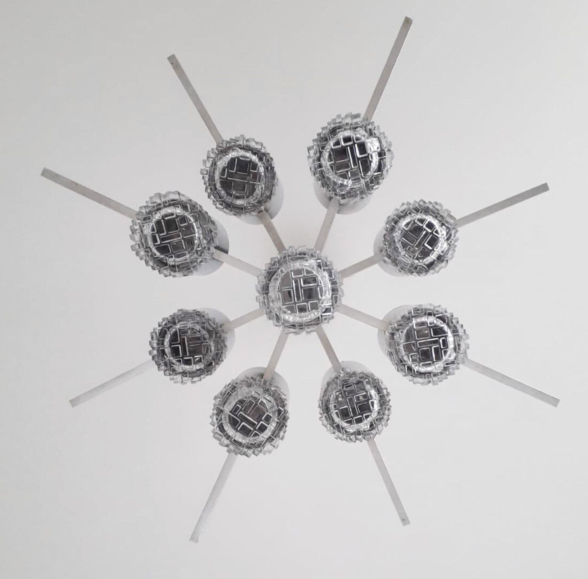 Llamativa lámpara de araña italiana vintage diseñada por Gaetano Sciolari, hacia la década de 1970. Esta escultural luminaria cuenta con nueve difusores geométricos de cristal que proporcionan una luz refinada y resplandeciente. Los difusores están