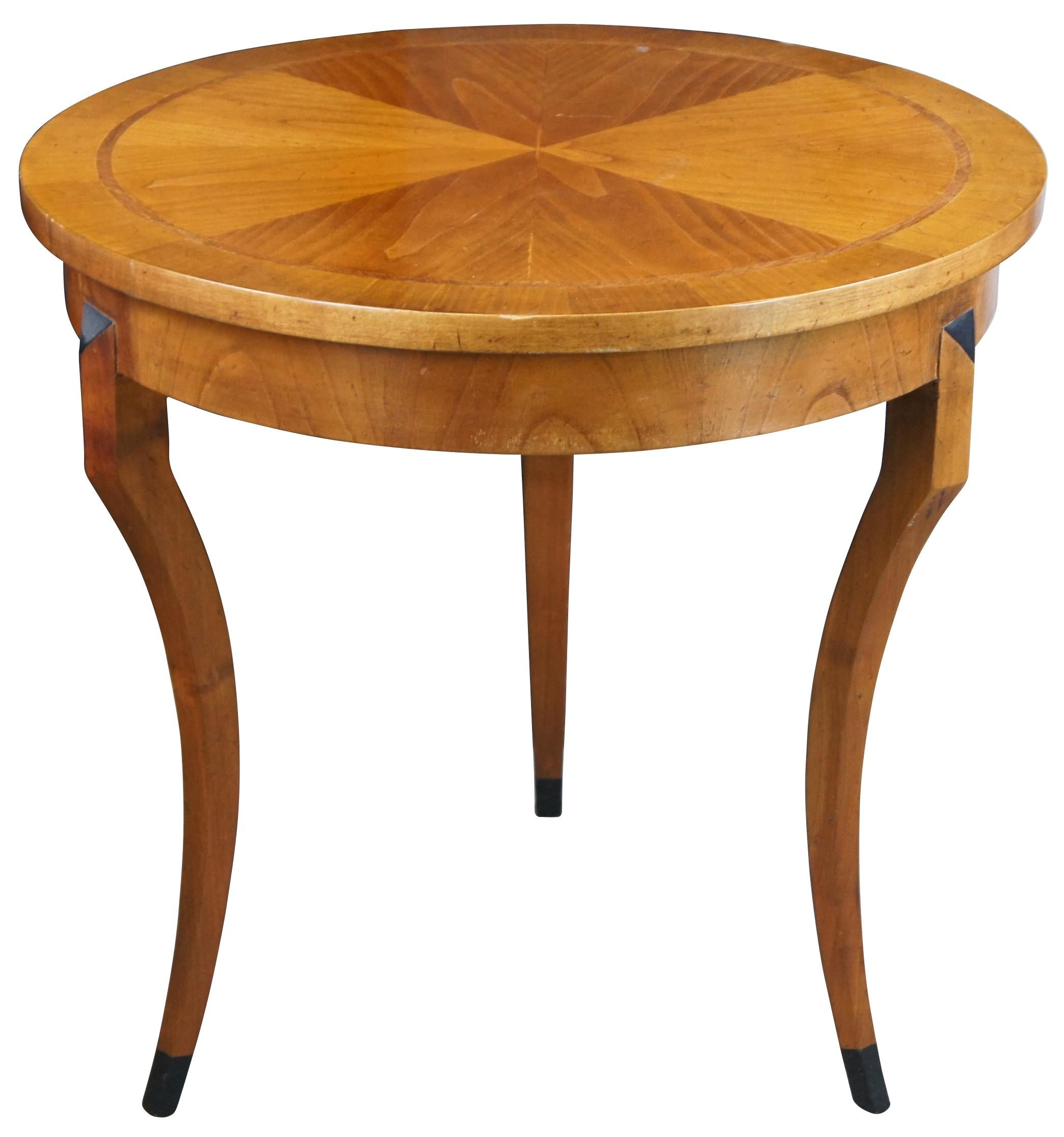Italian crafted Gueridon table in Biedermeier form, circa last quarter 20th century. Features a round top made from Cherry with matchbook veneer and banding over three saber legs with ebonized trim. Naturally distressed finish. Marked along