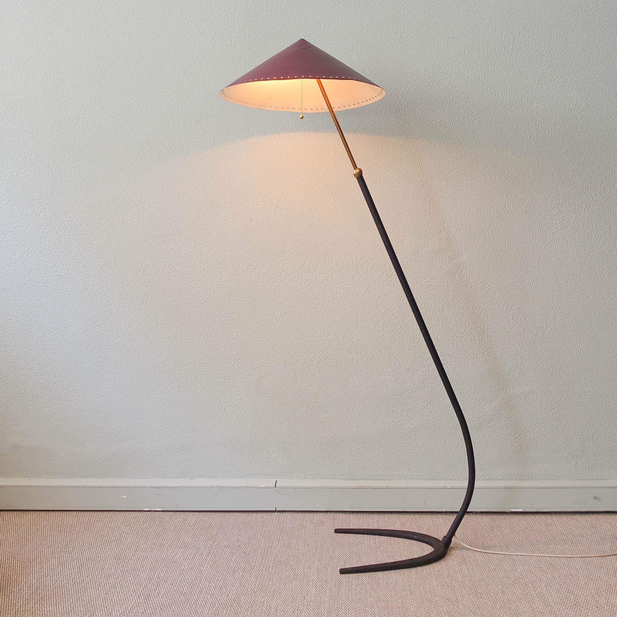 This floor lamp was designed and manufactured in Italy during the 1950's. It features a black metal semi circle base, that continues through a metal stem, that finishes in brass. The triangular conical lampshade (chinese hat) is in metal, lacquered