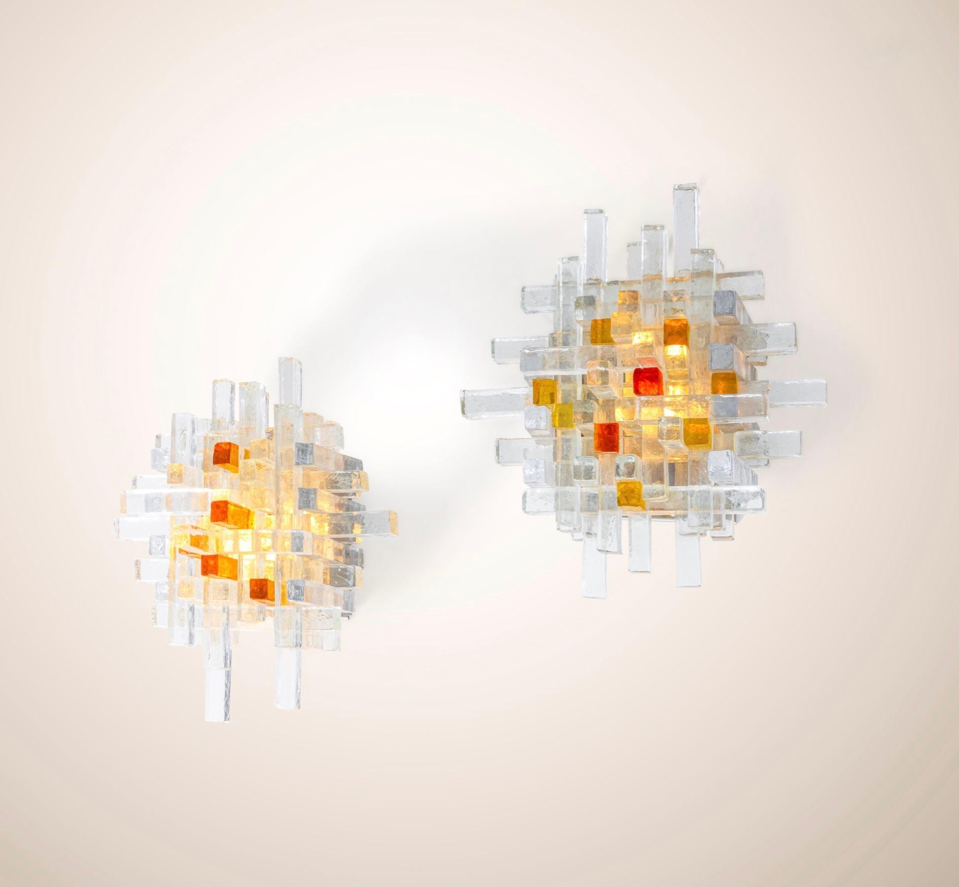 Vintage Italian sconces made in the c. 1960's, having a chrome frame and Murano glass rods. The interlocking of the rods give the wall lights an abstract feel, while the clear, amber and orange Murano glass blends perfectly in any type of setting.