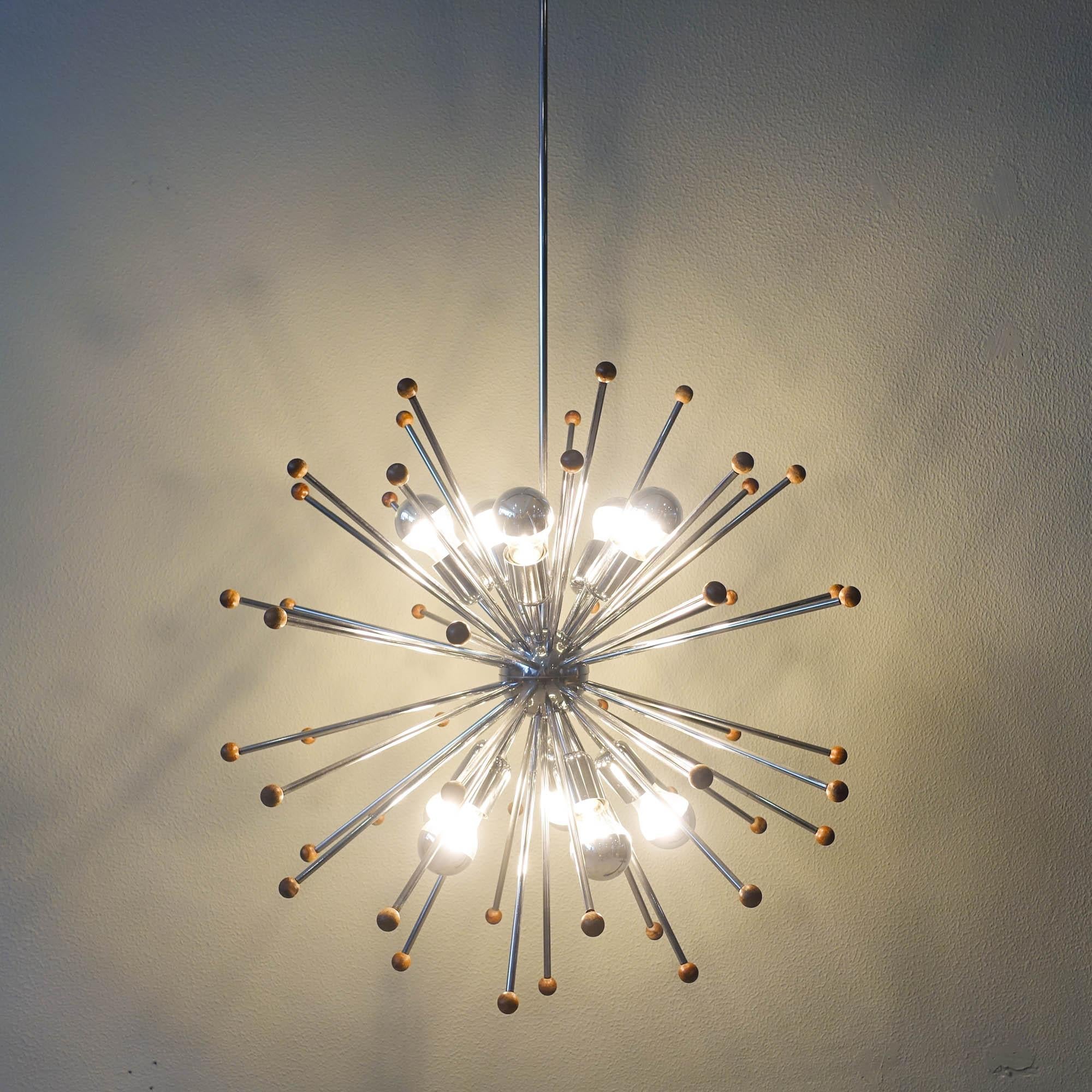 This ceiling lamp was designed and produced in Italy during the 1970's. It is a large chromed Sputnik chandelier with 10 light points. With a chrome globe in the middle were chromed metal rods are attached and point in every direction with teak