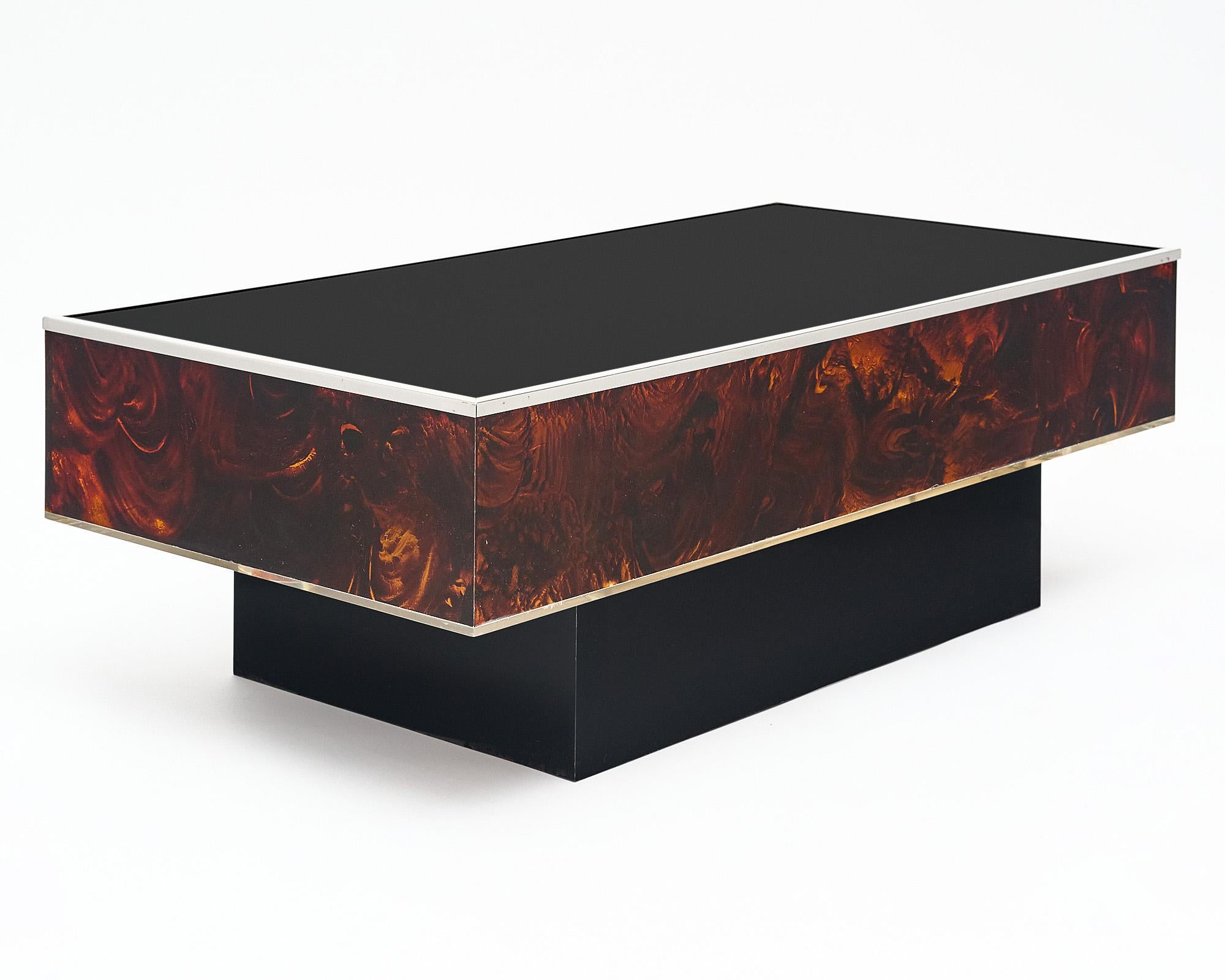 Coffee table from Italy made with Lucite and glass. This piece has sides of Lucite that are patterned to resemble burled wood. The top is black glass and is trimmed with chrome. The rectangular table sits on a black base. It lights up from within