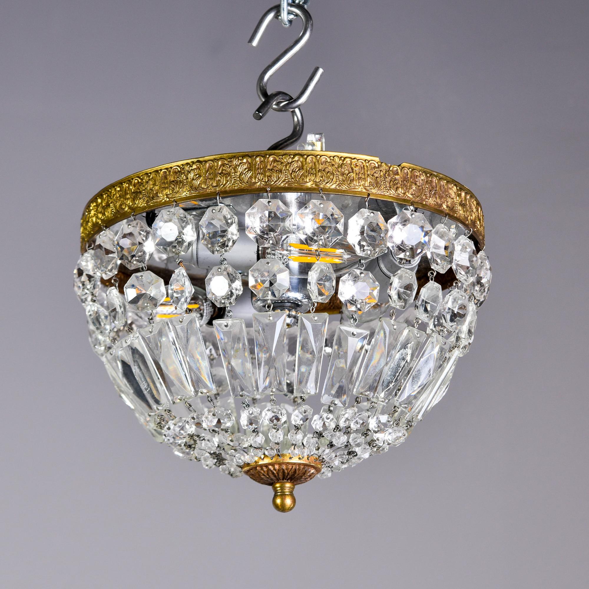 Found in Italy, this circa 1940s ceiling fixture has a pressed brass rim and crystals suspended in a basket form with a brass finial. Three internal candelabra sized sockets. New wiring for US electrical standards. Perfect petite fixture for a