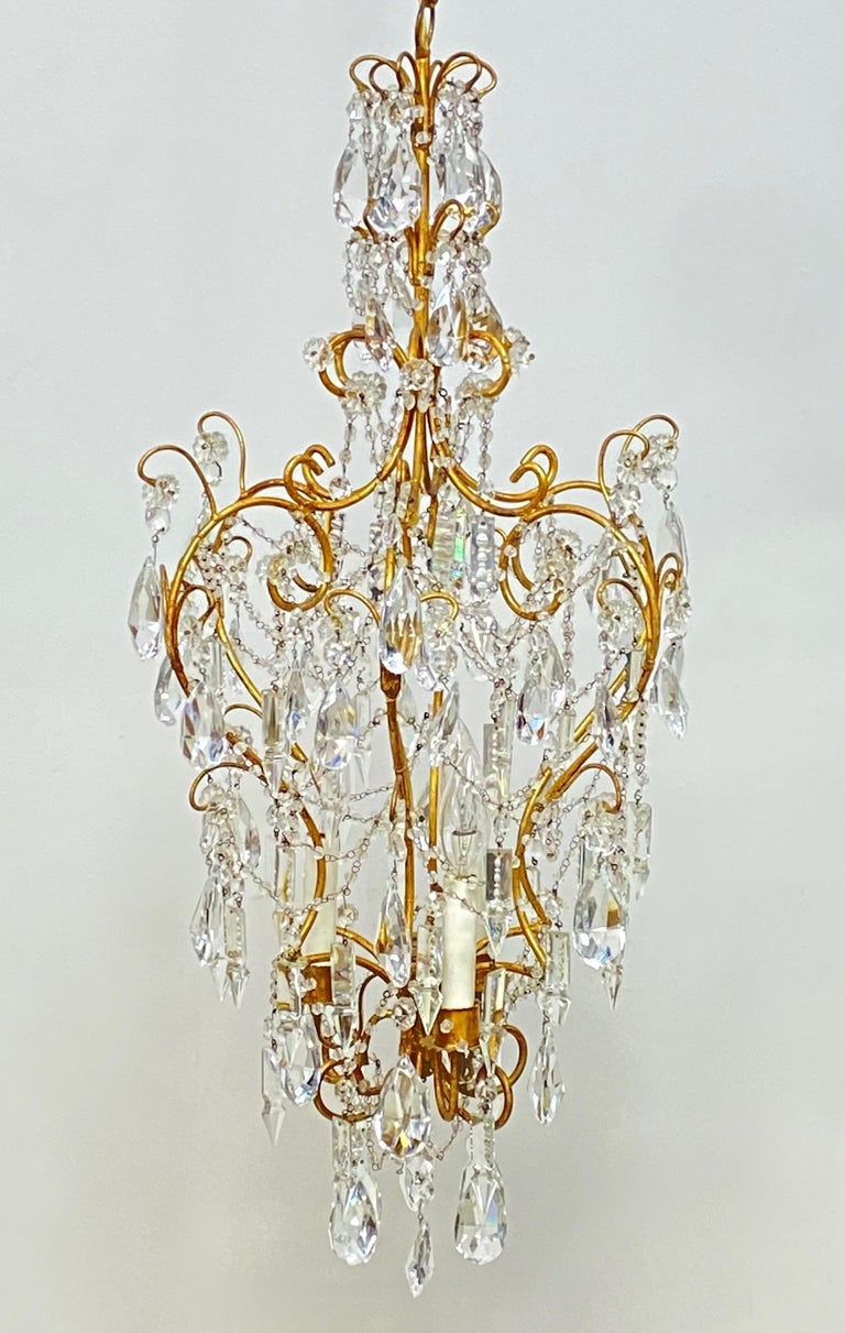 Small-scale crystal and glass pendant style chandelier. Having a gilt metal cage abundantly draped with crystal and glass swags and pendant drops.
Recently cleaned and re-wired. We can shorten the chain length to the buyer's specifications.
Italy,