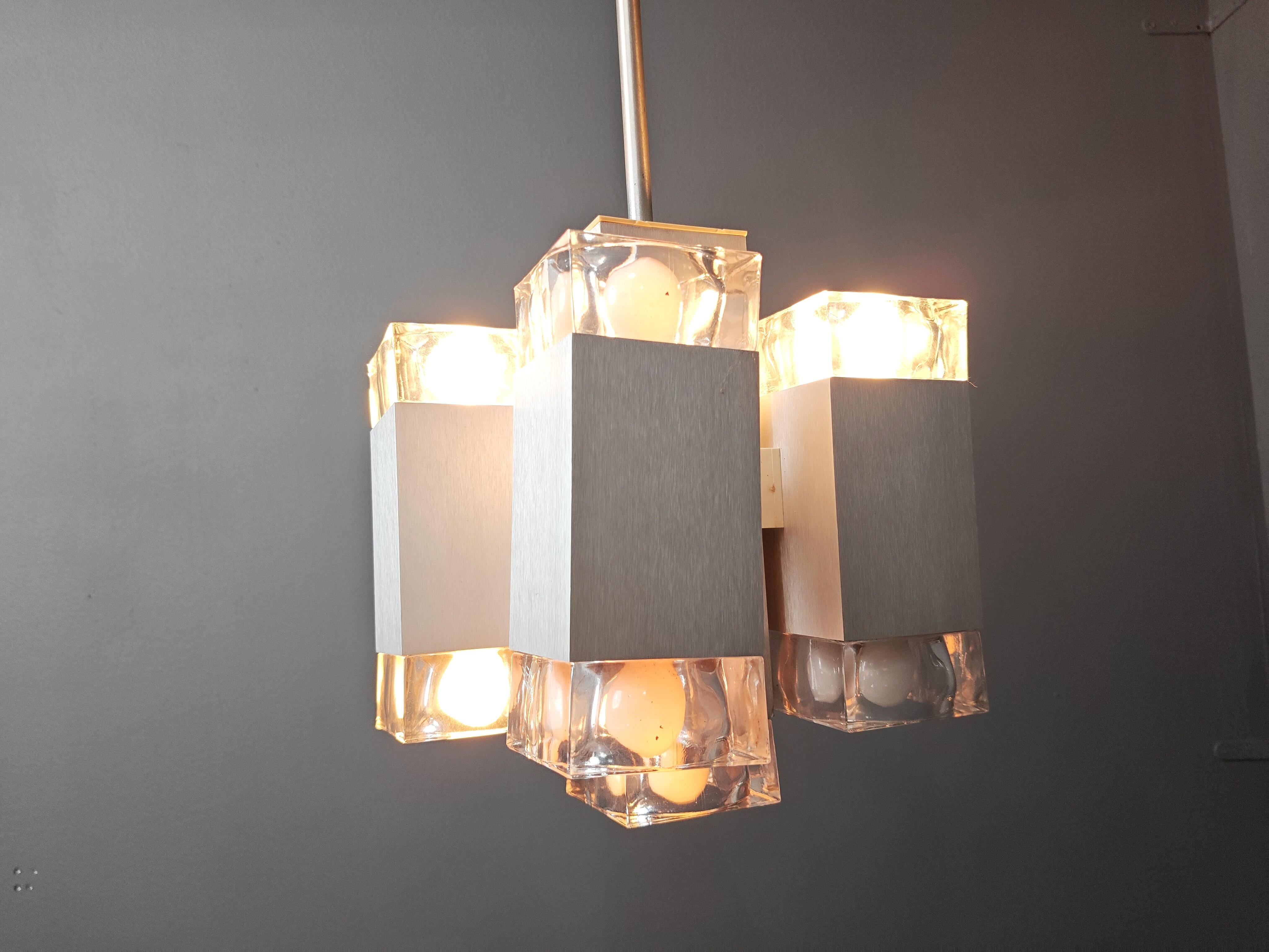 Lampadario modernista vintage alla maniera di Gaetano Sciolari composto da una struttura in alluminio con paralumi in vetro realizzati a mano.

Il design cubico è molto attraente e il lampadario emette una luce bellissima.

Il lampadario ha 9