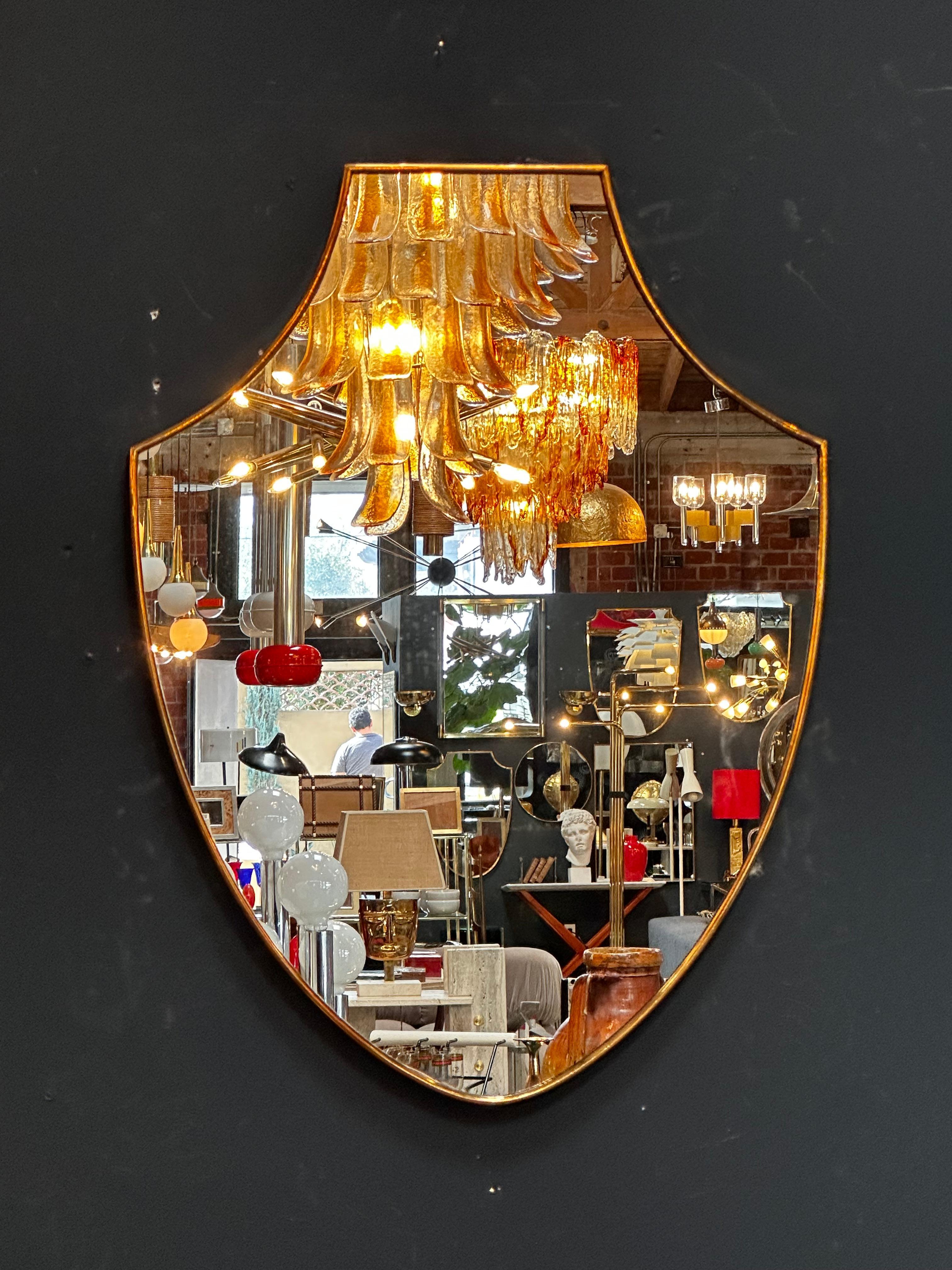 The Vintage Italian 1960s Curvilinear Brass Wall Mirror is a stylish and unique piece showcasing elegant curves in brass.

