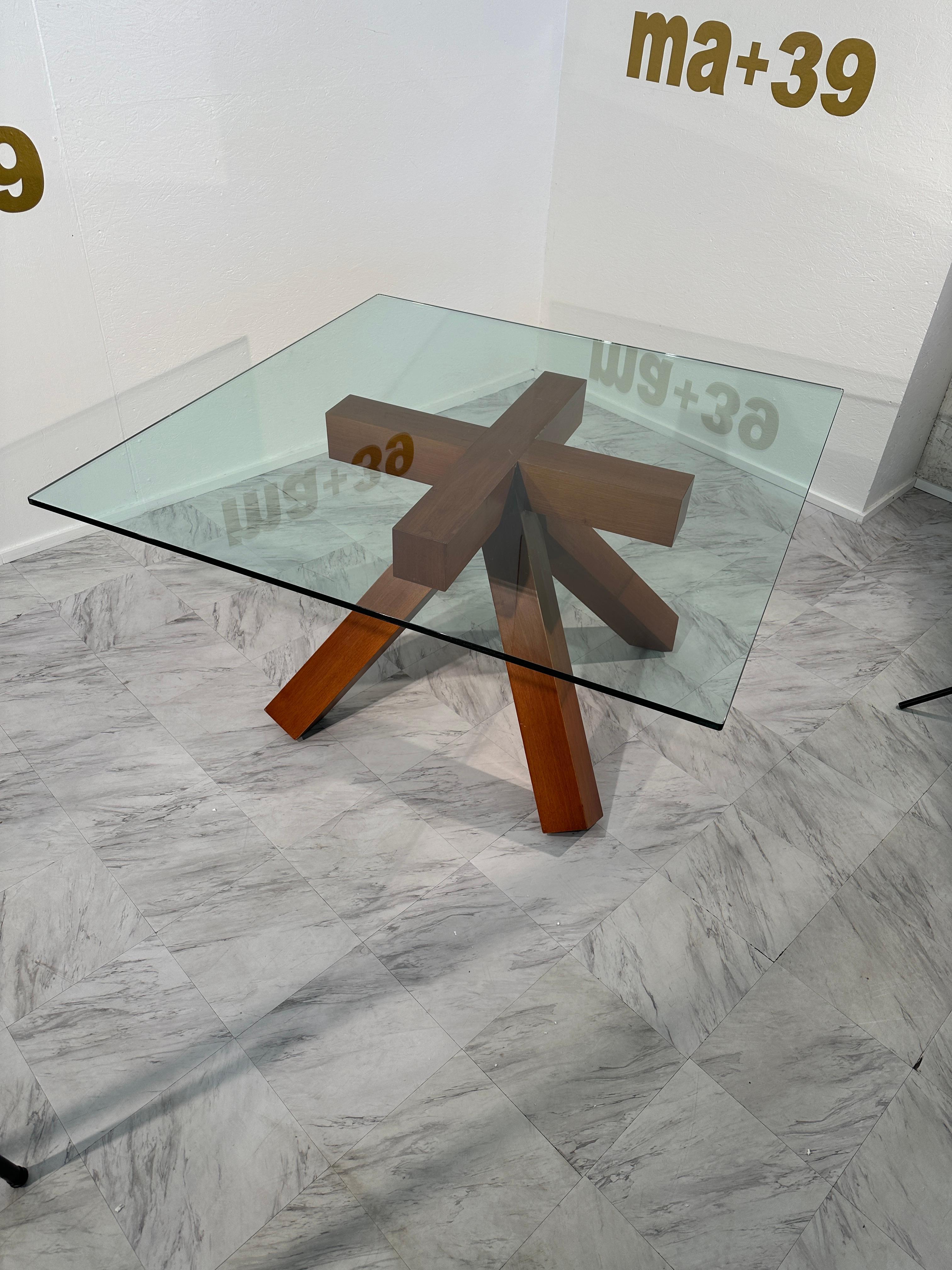 The Vintage Italian Nutwood and Glass Dining Table, known as La Rotonda and designed by Mario Bellini for Cassina in the 1970s, is a stunning representation of mid-century modern design. The table features a square glass top that allows for a clear